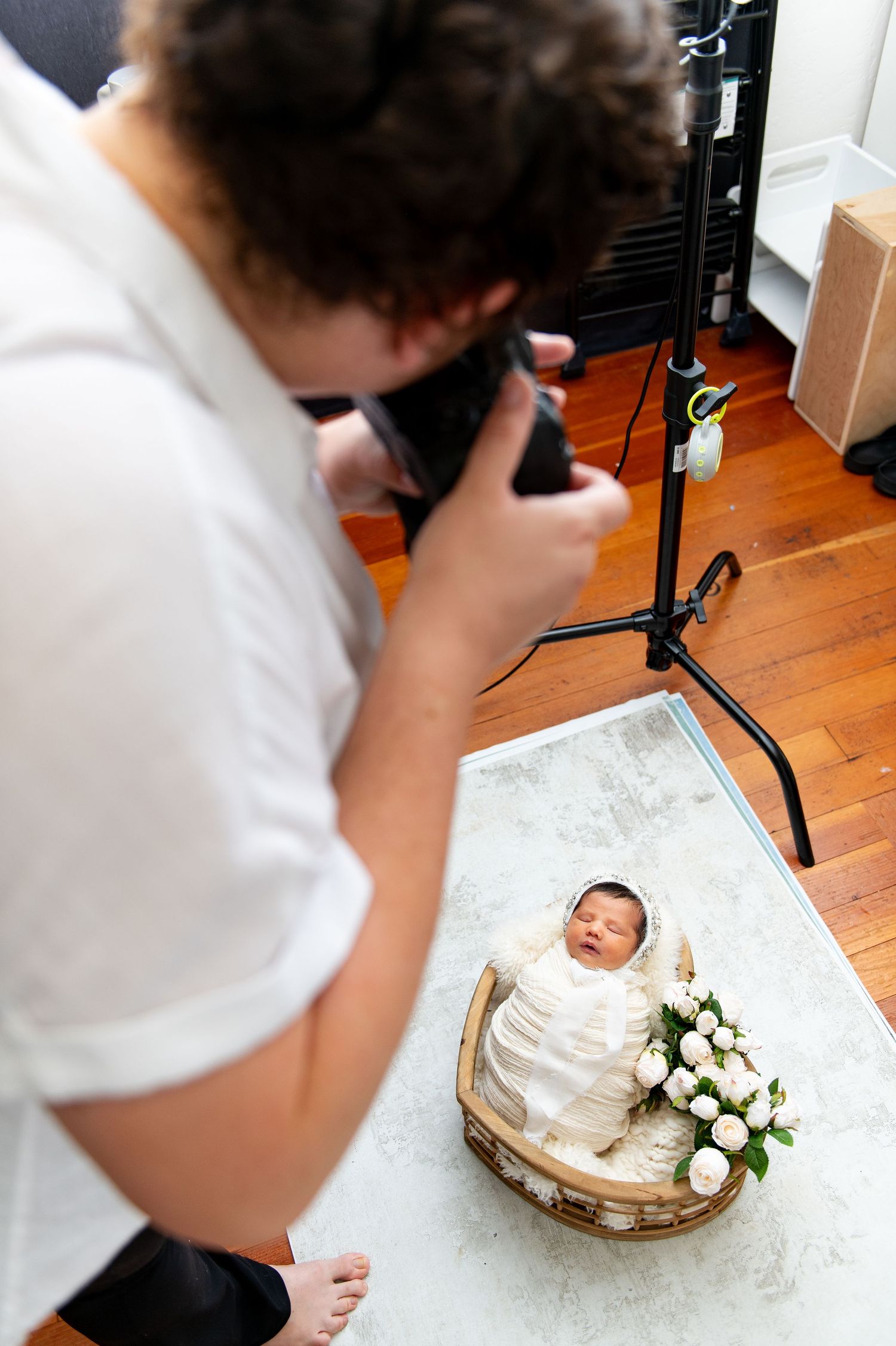 A series of photos showing someone photographing a white wedding cake with roses on a wooden floor.