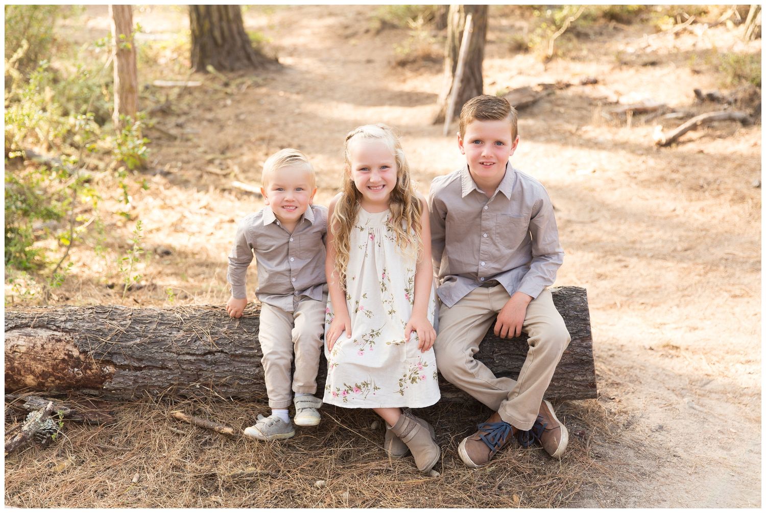 A group sits casually on a rustic dirt path surrounded by natural scenery during an outdoor photo session.
