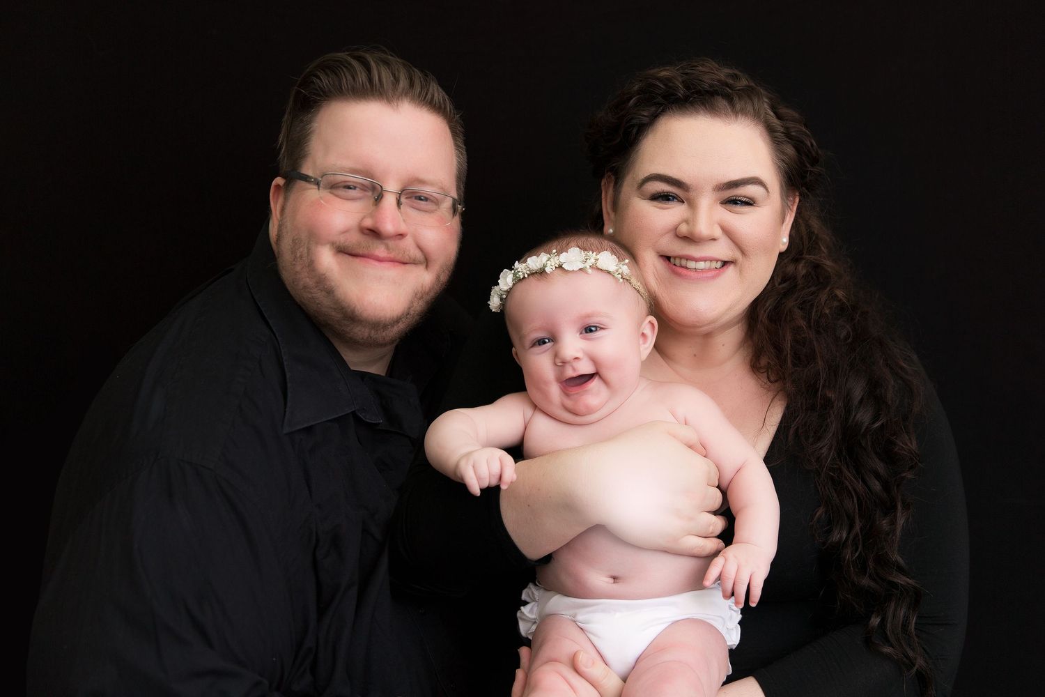 A heartwarming family studio portrait against a black background.
