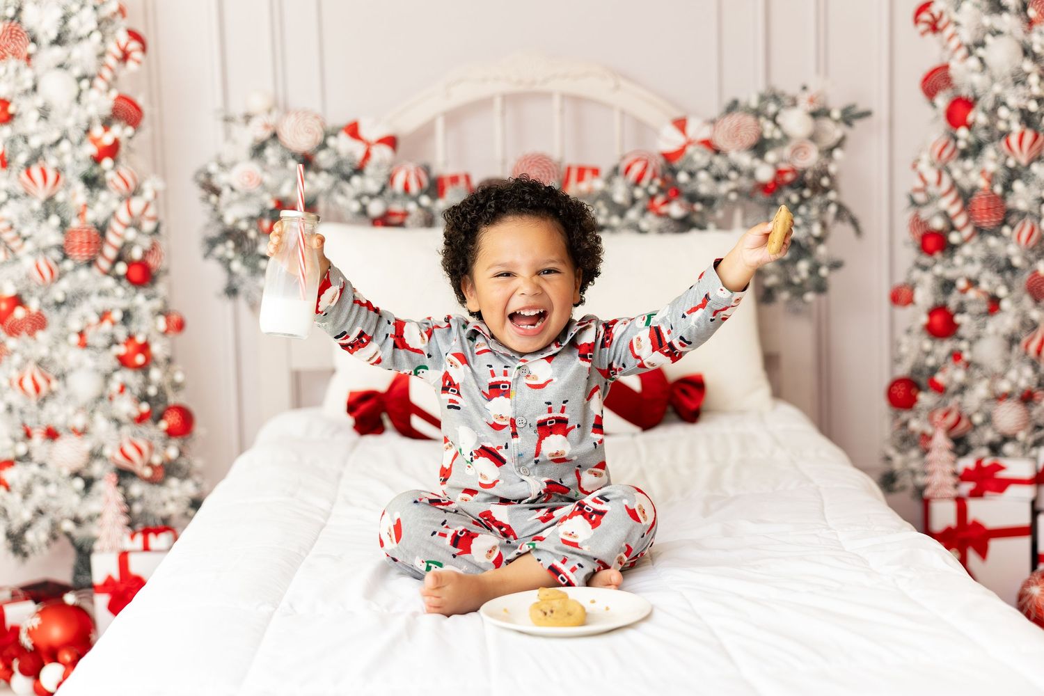 Holiday portrait featuring coordinated sleepwear against a red and white floral Christmas backdrop.