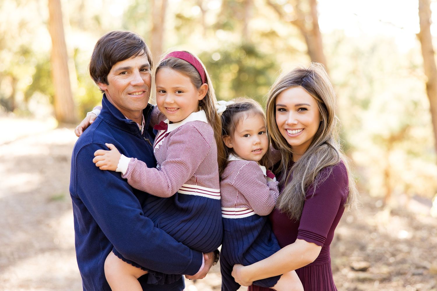 Intimate family portraits taken in a sun-dappled forest setting.