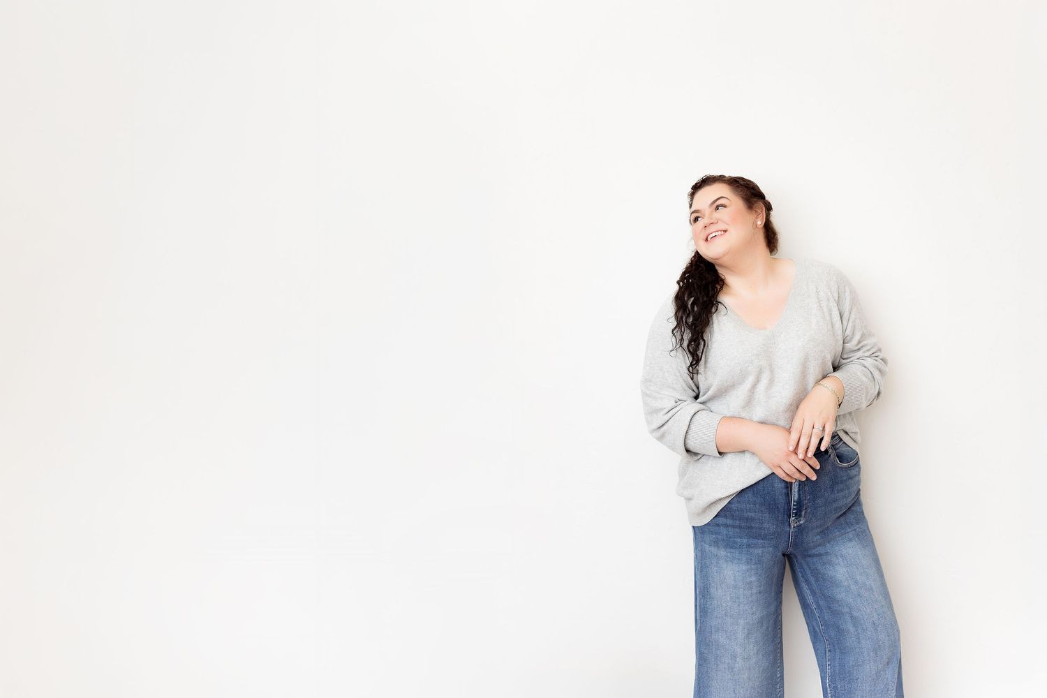 A four-panel collage showing someone wearing blue jeans and a gray sweater in different casual poses against a white backdrop.