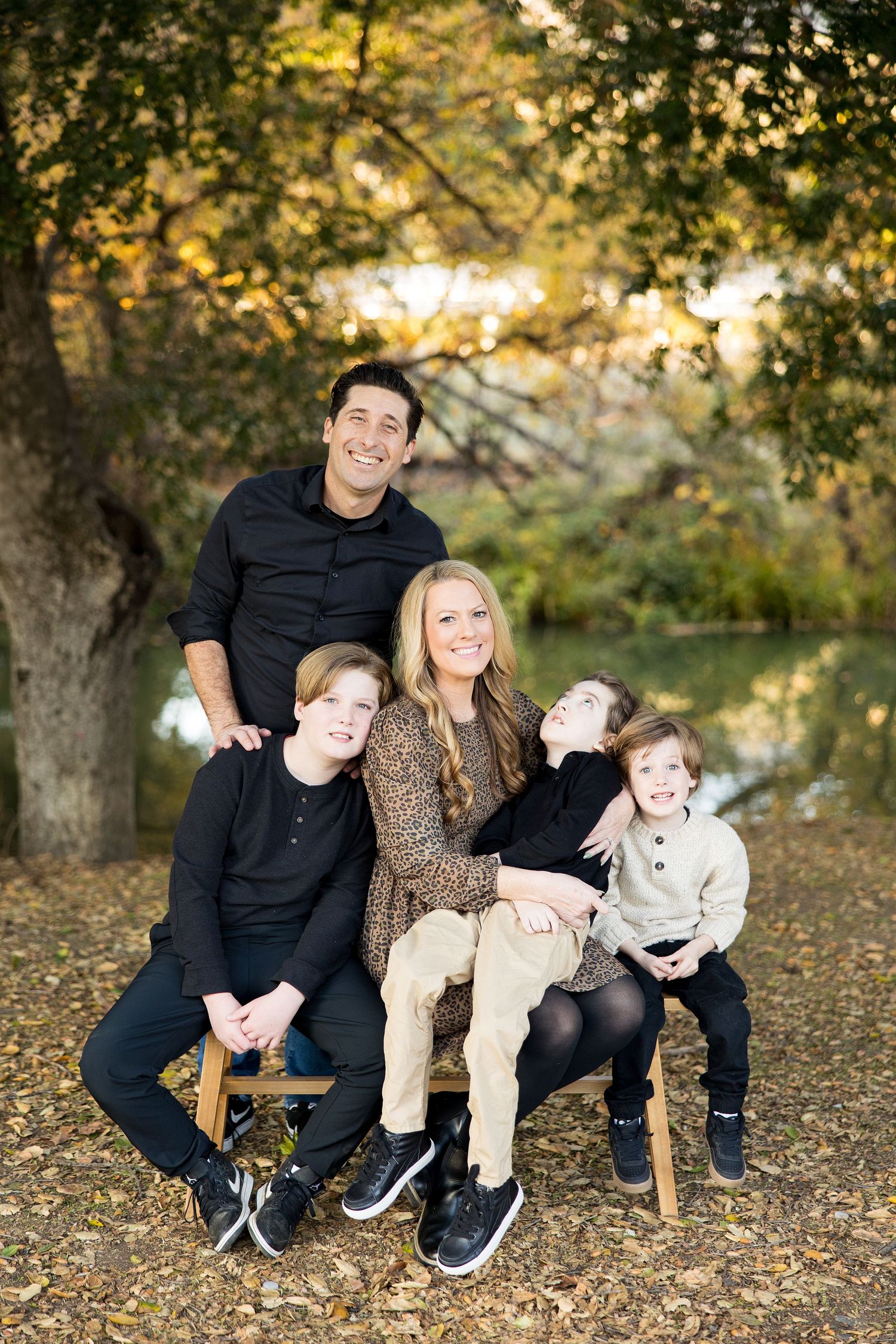 Casual family photo shoot in an autumn park setting with fallen leaves.