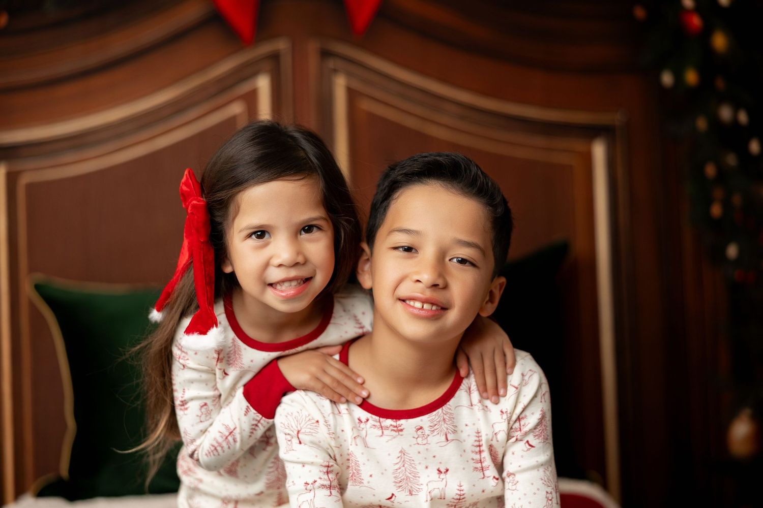 Two kids in matching Christmas jammies smiling together at a holiday mini session in Pacific Grove
