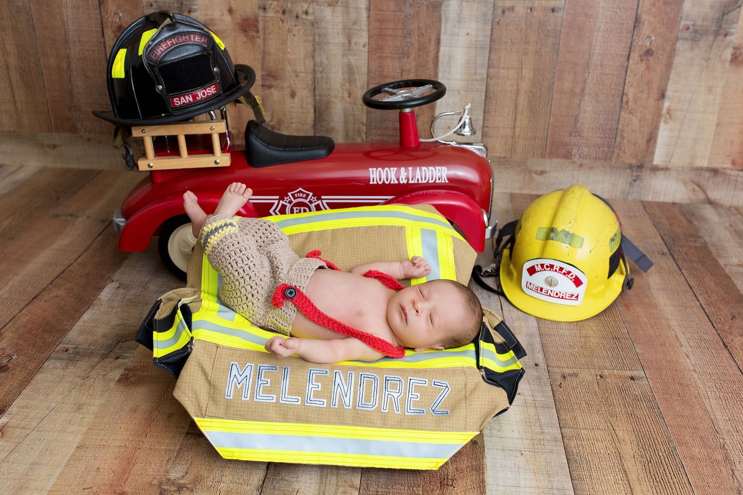 A series of firefighter gear and equipment laid out on wooden flooring including reflective vests and helmets.