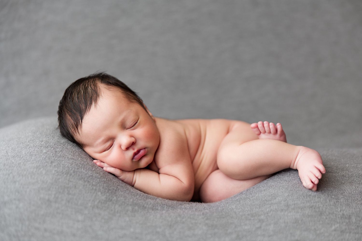 Minimalist newborn photography collection on grey backdrop showing peaceful sleeping poses.