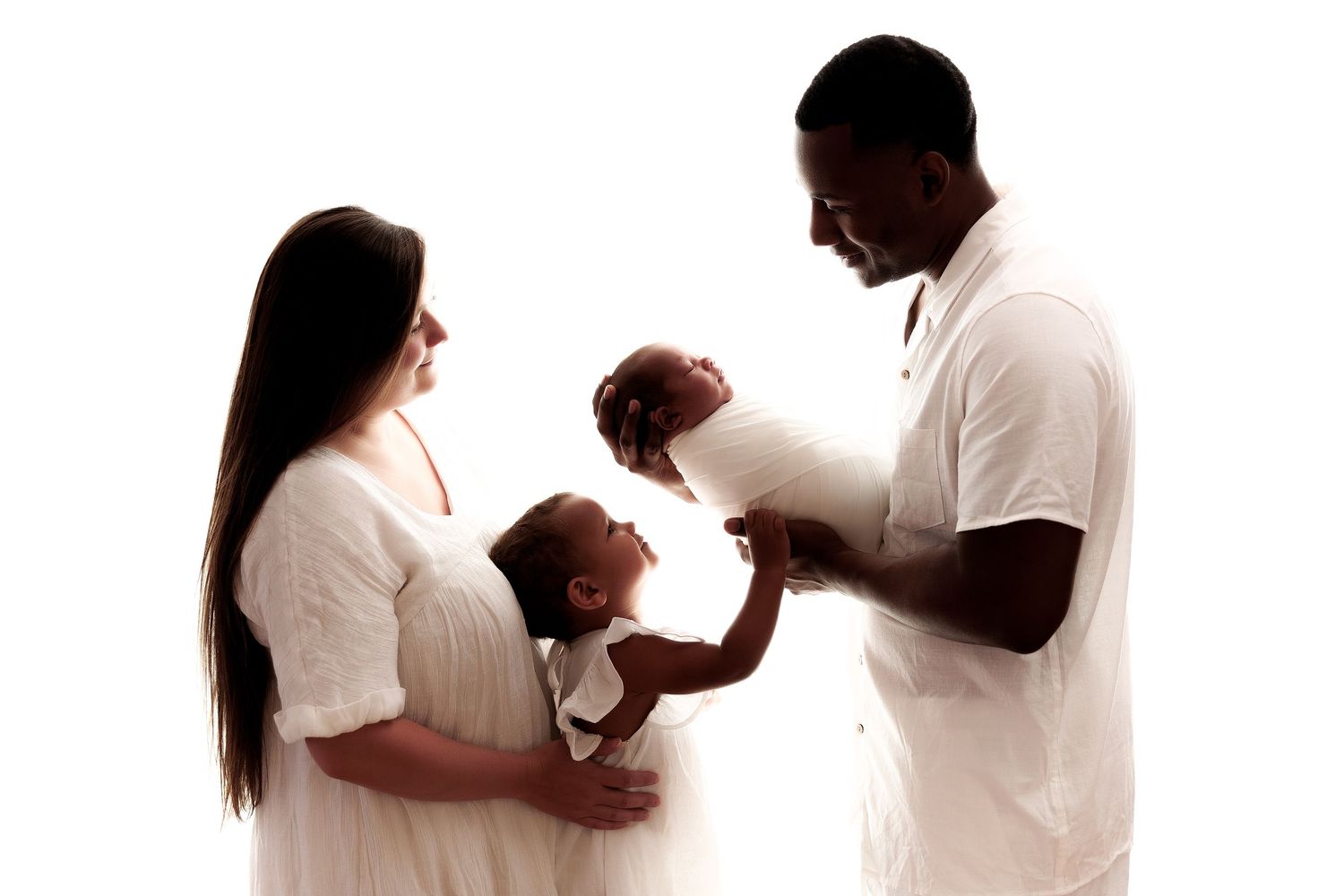 Family wearing white clothing poses together in elegant silhouette series.
