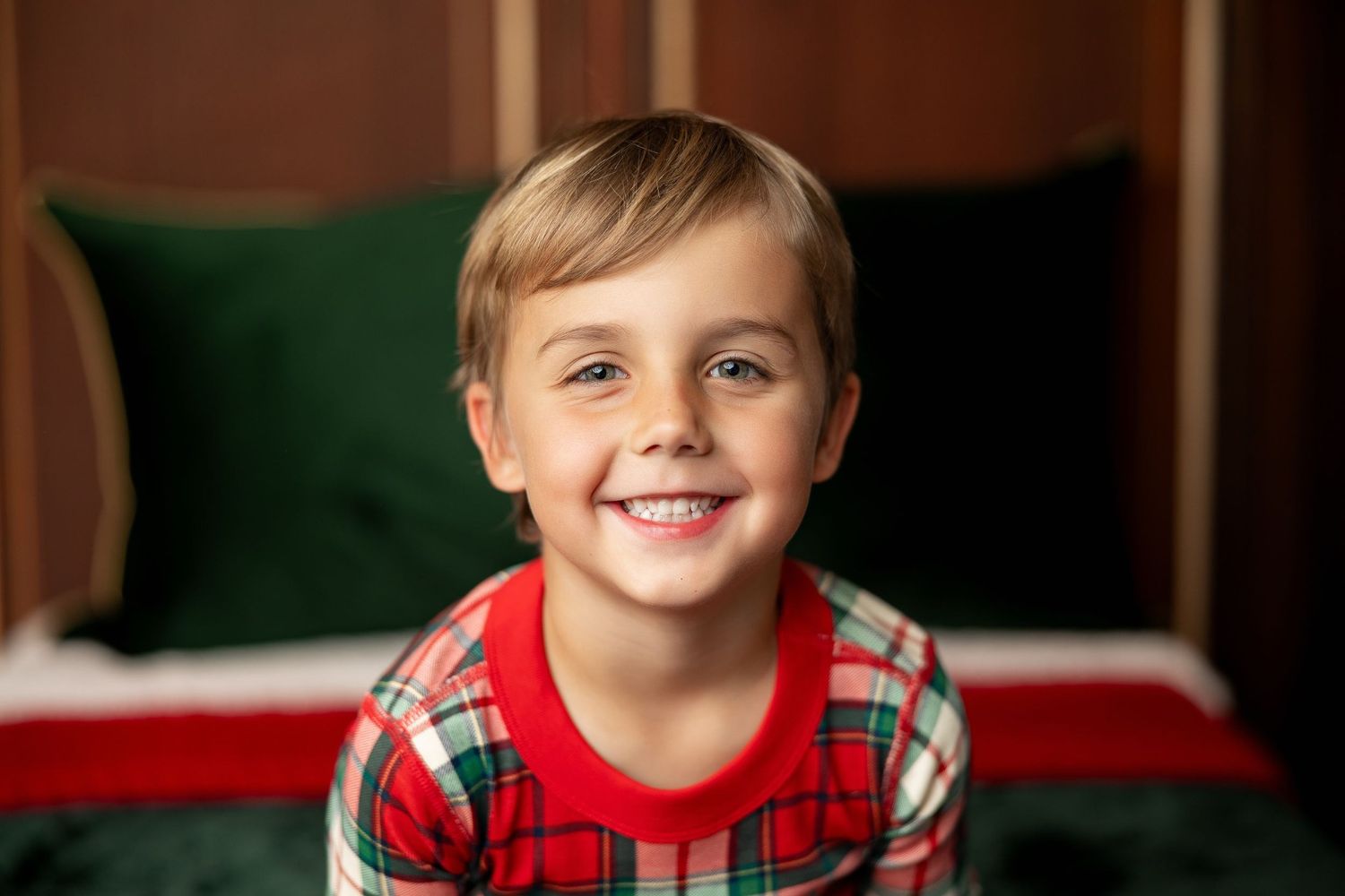 Cheerful boy in red plaid Christmas pajamas at a Milk & Cookies holiday mini session in Pacific Grove