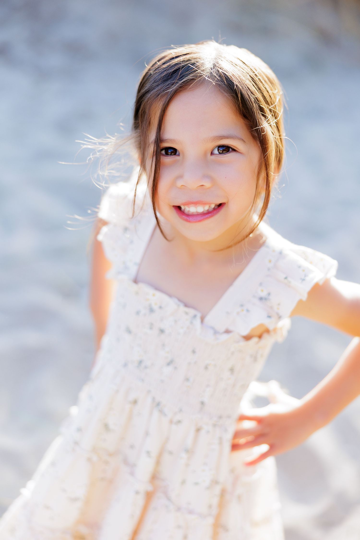 Smiling little girl in a cream dress on the beach dunes during a Santa Cruz family photo session.