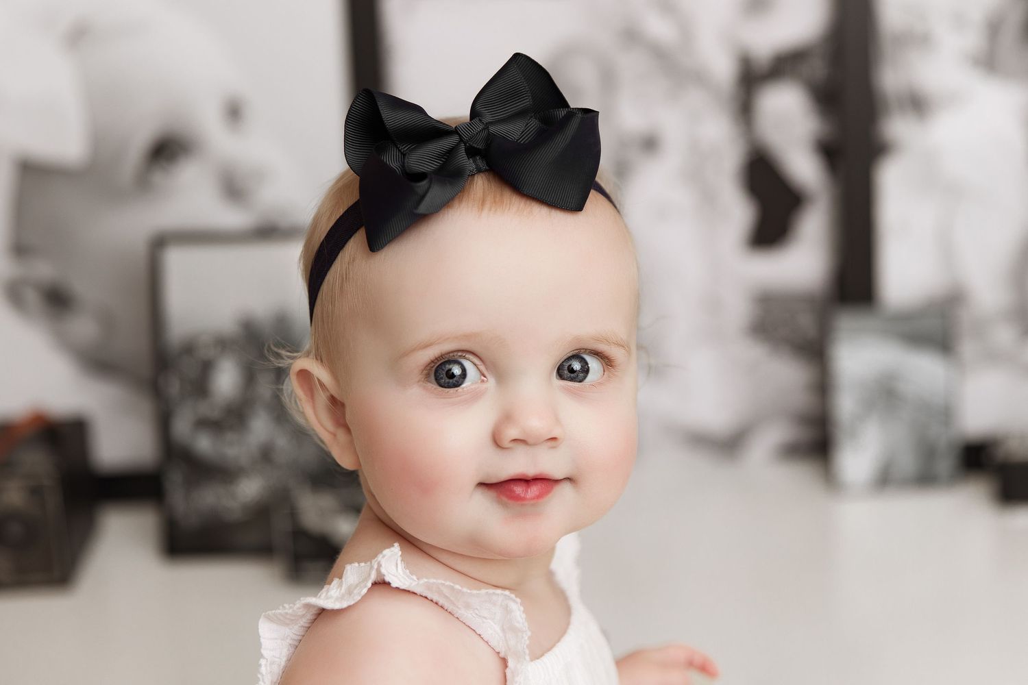 Sweet baby portrait with black bow headband in black and white style.