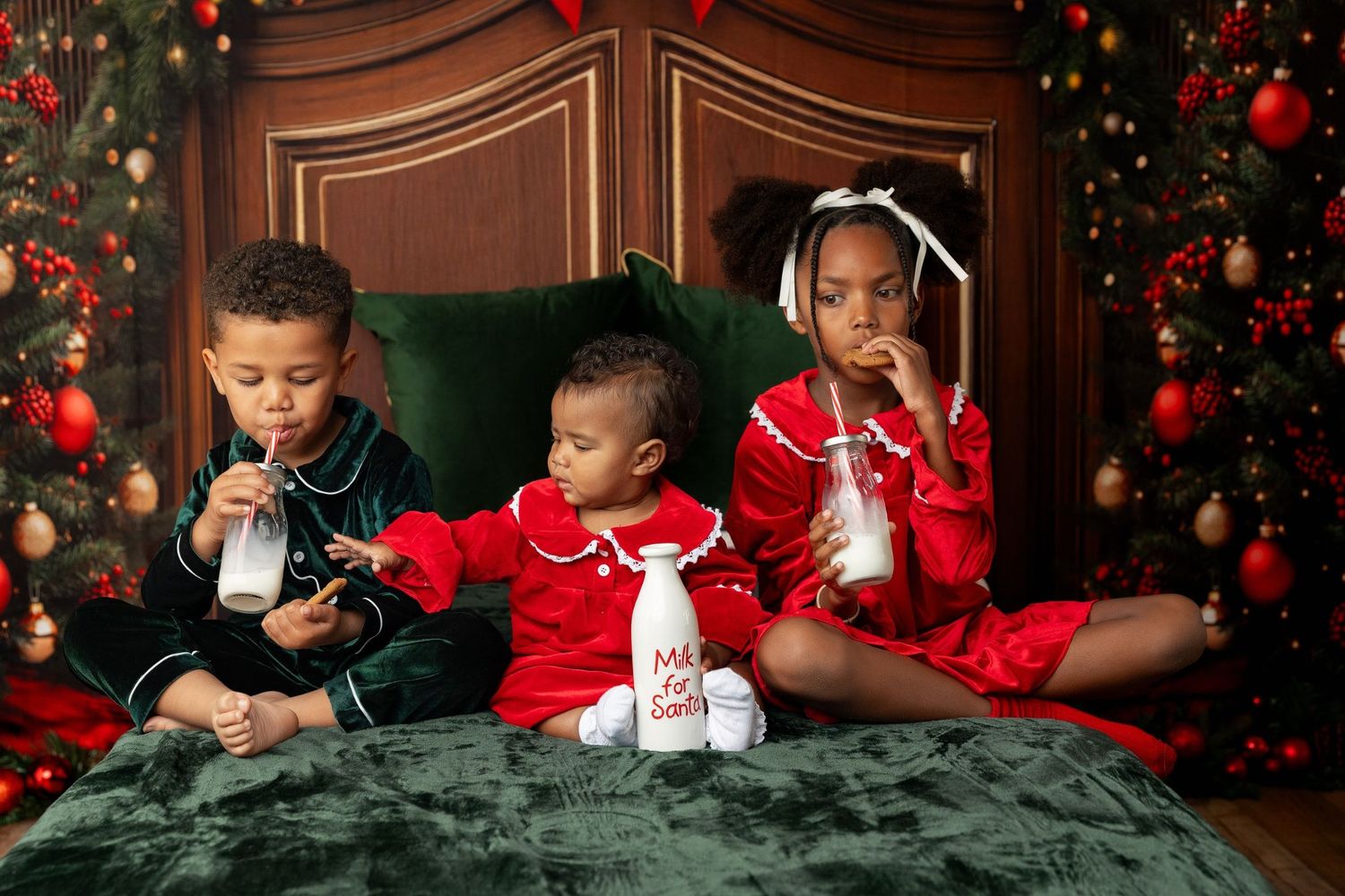 Three kids in Christmas pajamas drinking milk on a green velvet bed at a holiday mini session in Pacific Grove