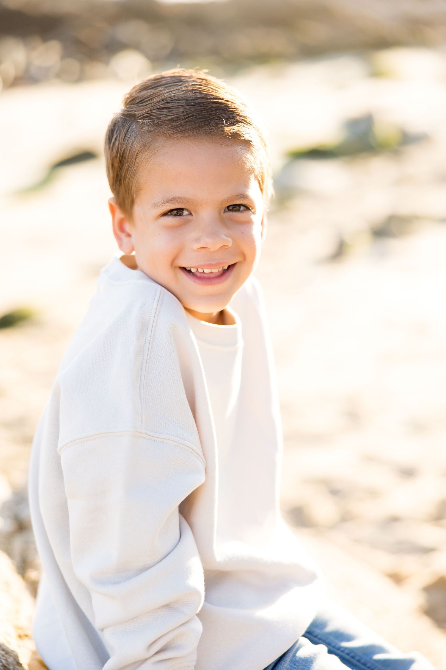Bright outdoor portraits in a white sweater against a sandy beach backdrop.