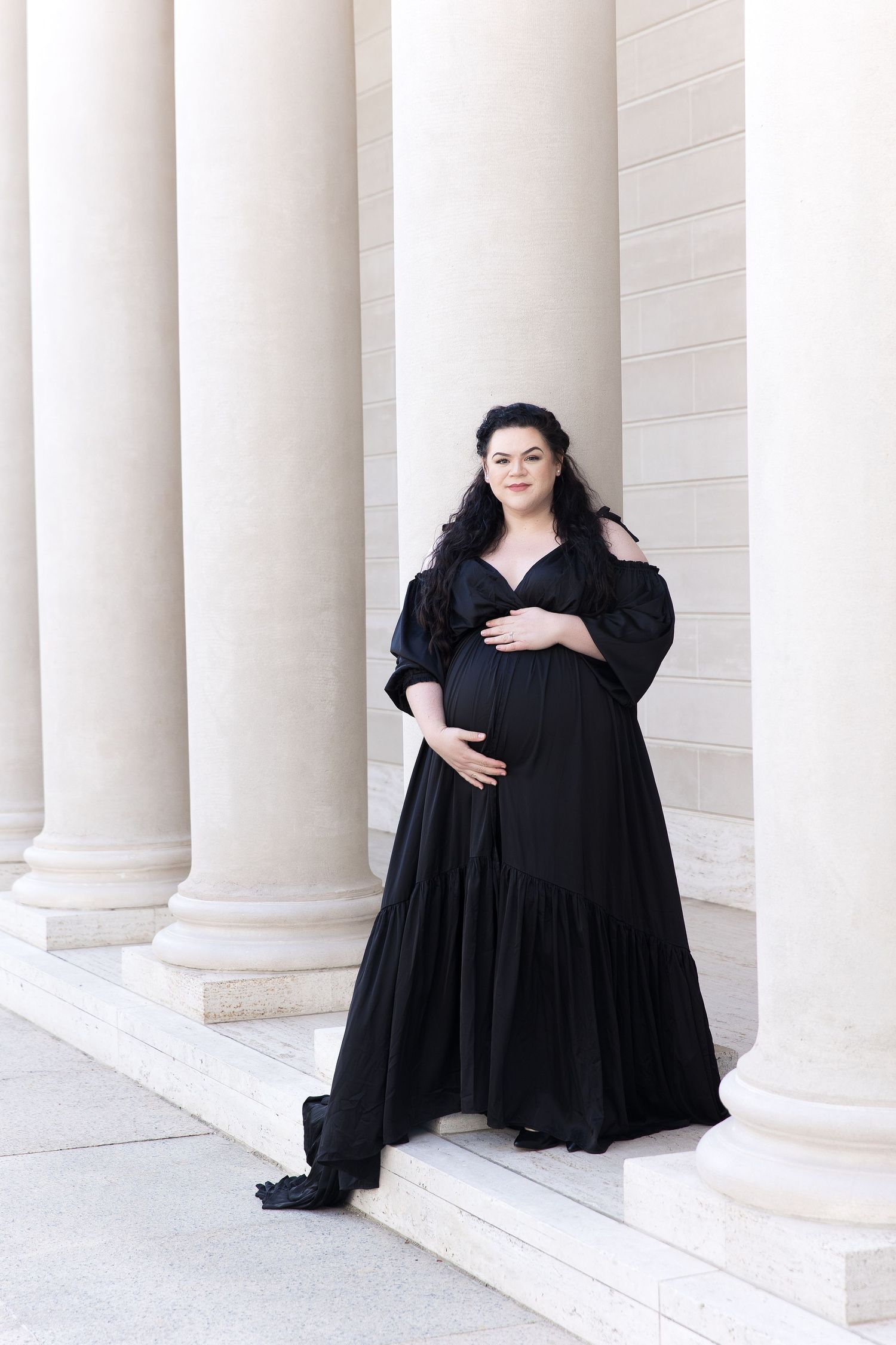 Dramatic black dress portraits among white pillars in architectural setting.