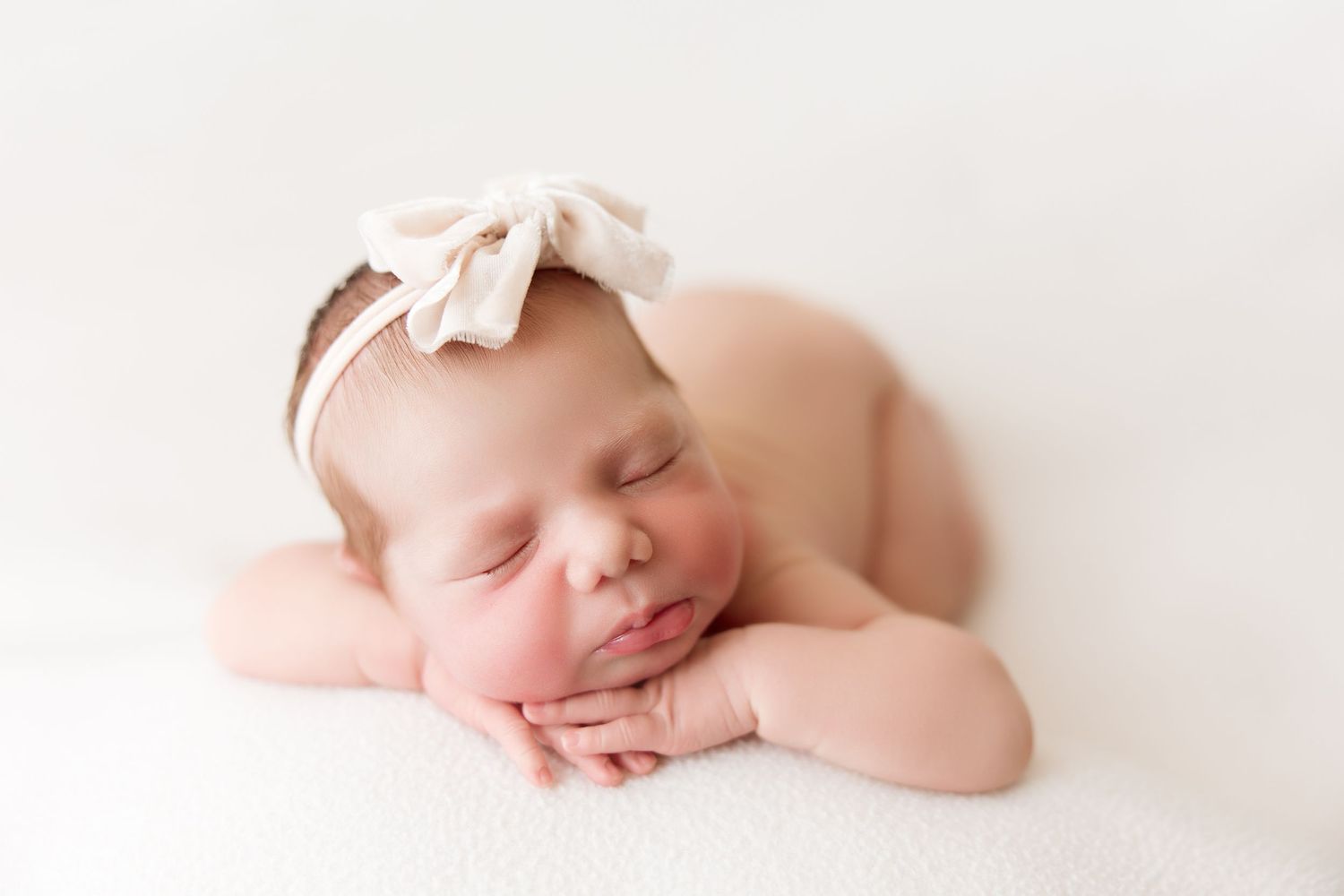 Sweet sleeping newborn baby wrapped in soft white fabric against white background.