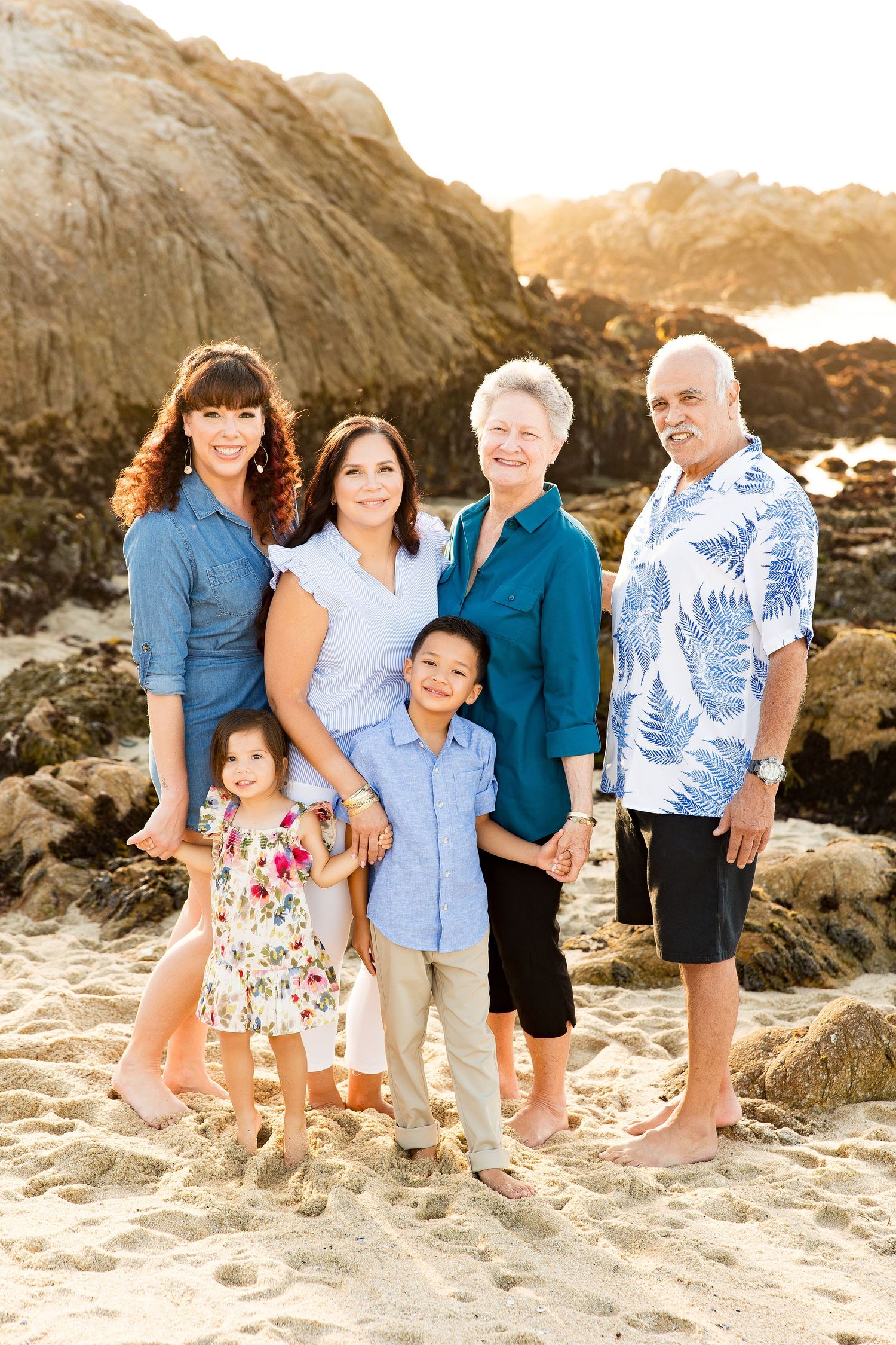 Family beach portrait session at sunset among rocky coastal formations of Asilomar beach.