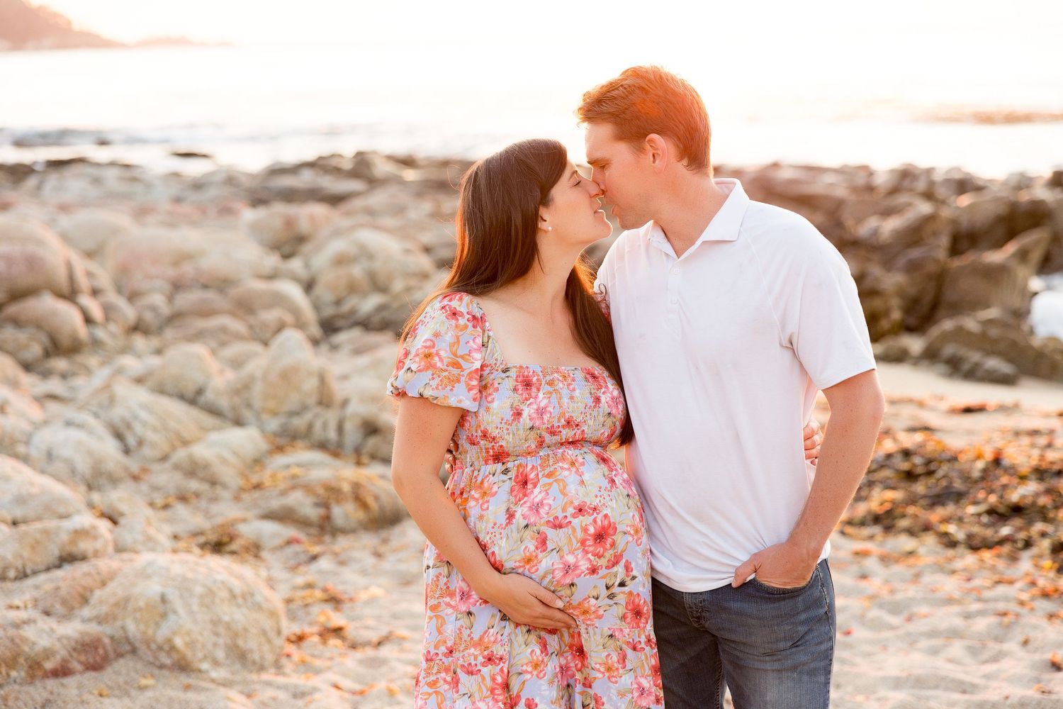 Couple sharing intimate moment on rocky beach at sunset.