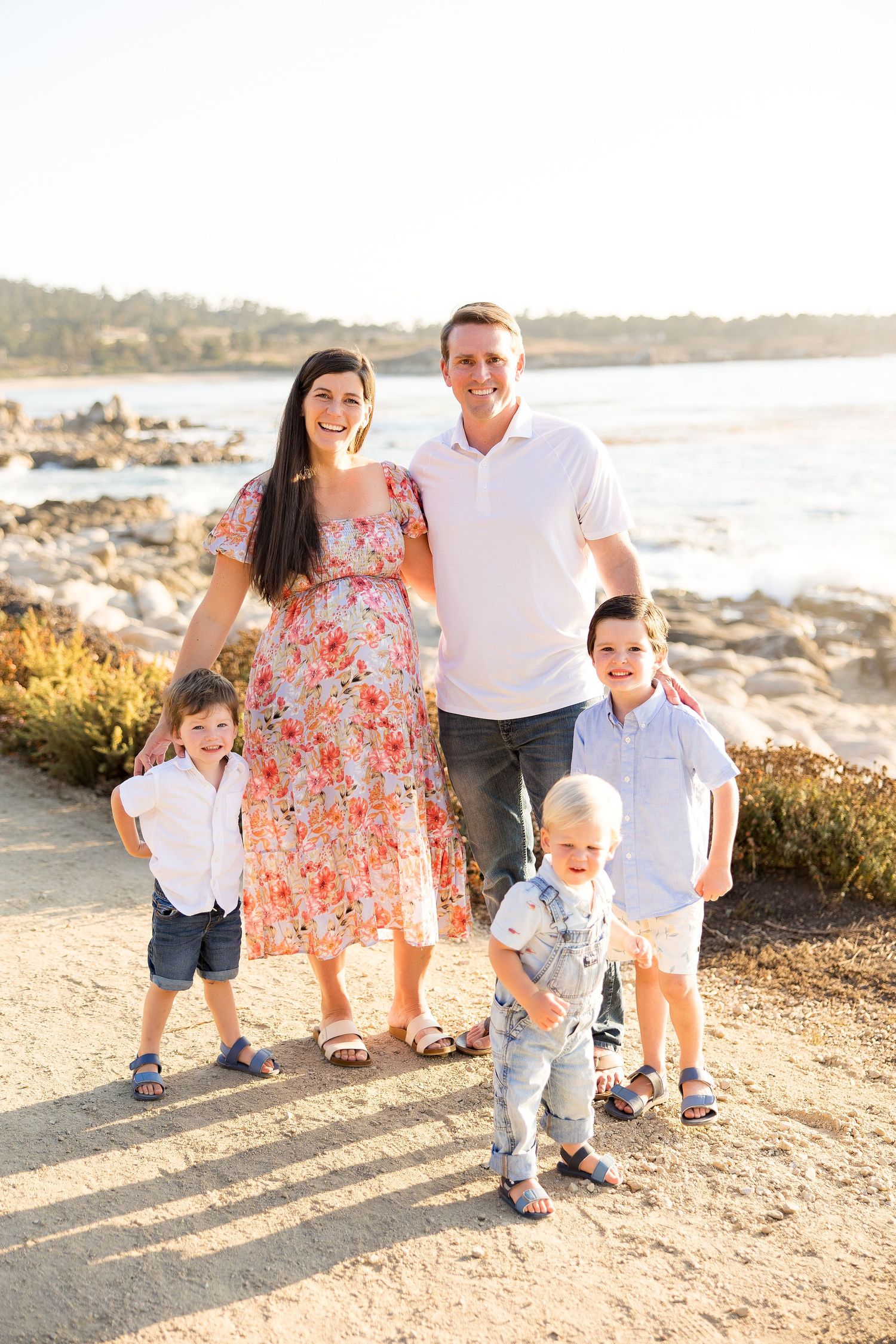 Family walking together on a beach path during golden hour.