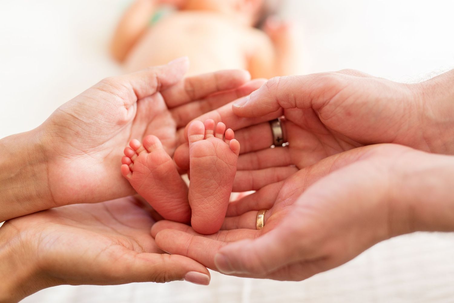 In-home lifestyle newborn photograph of feet and toes in parents hands in Monterey home