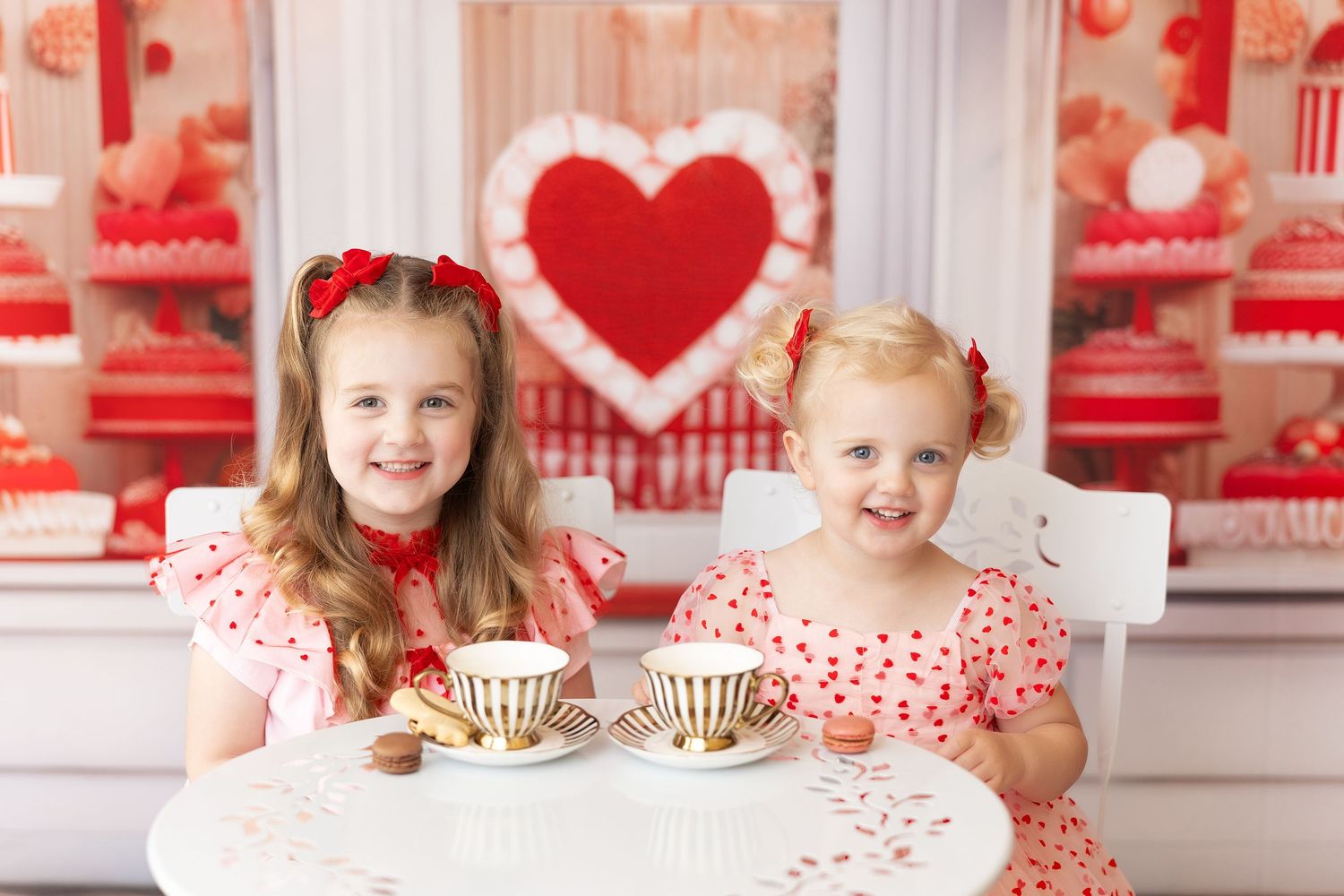 Two children enjoying tea time at a Valentine's themed party with heart decorations and red accents.