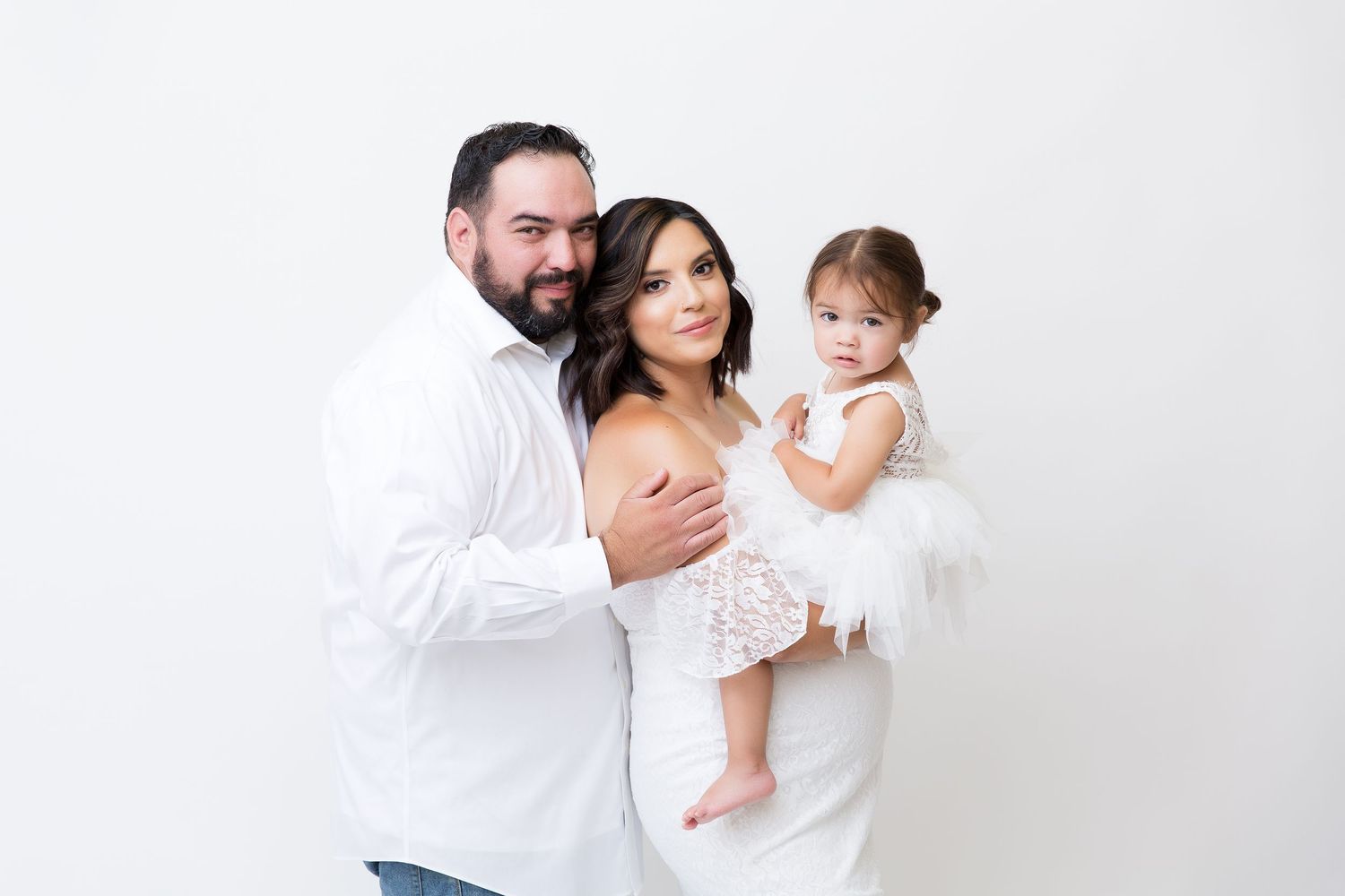 Family portrait in white attire against clean white background.