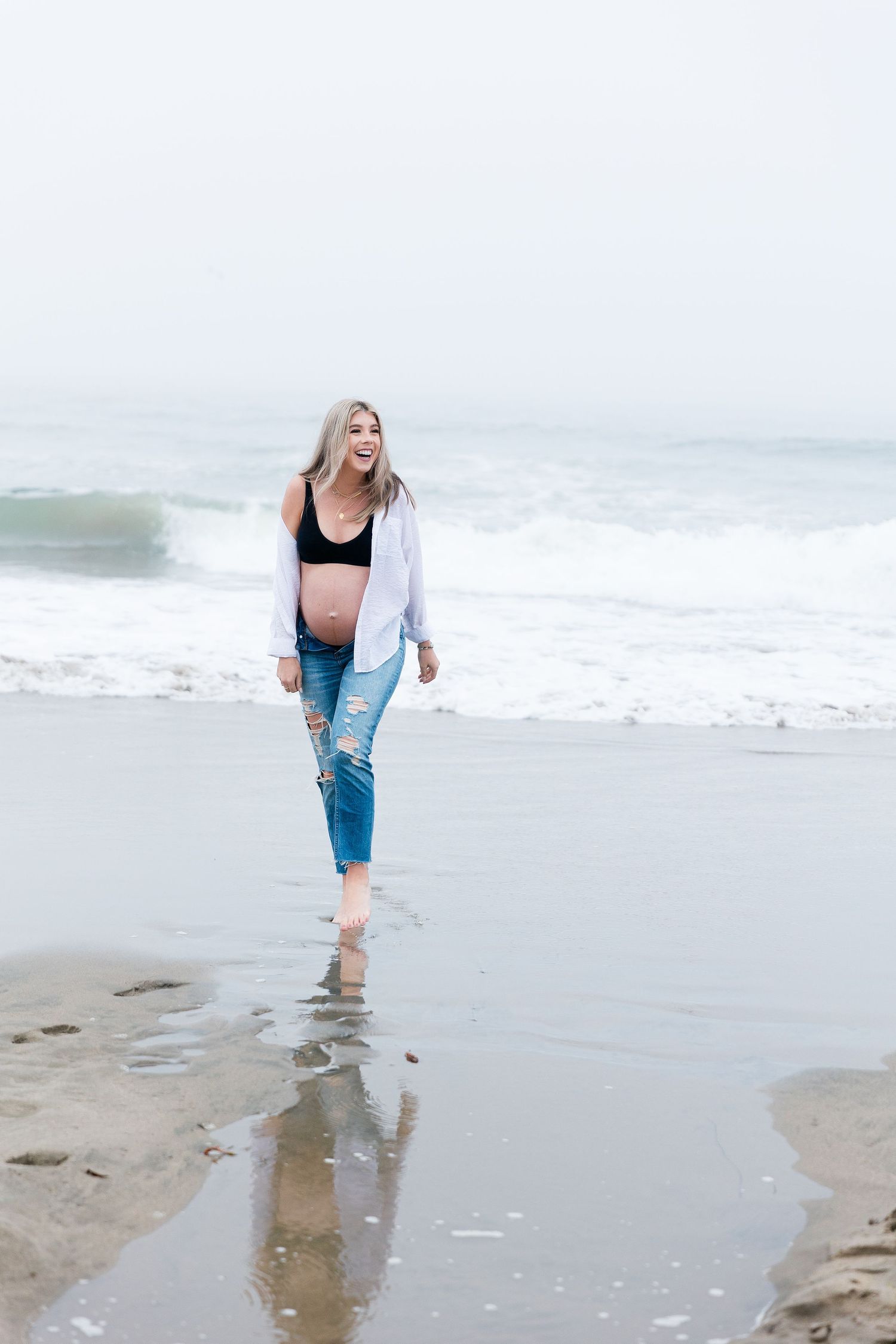 Person playing and splashing in ocean waves along a sandy beach.