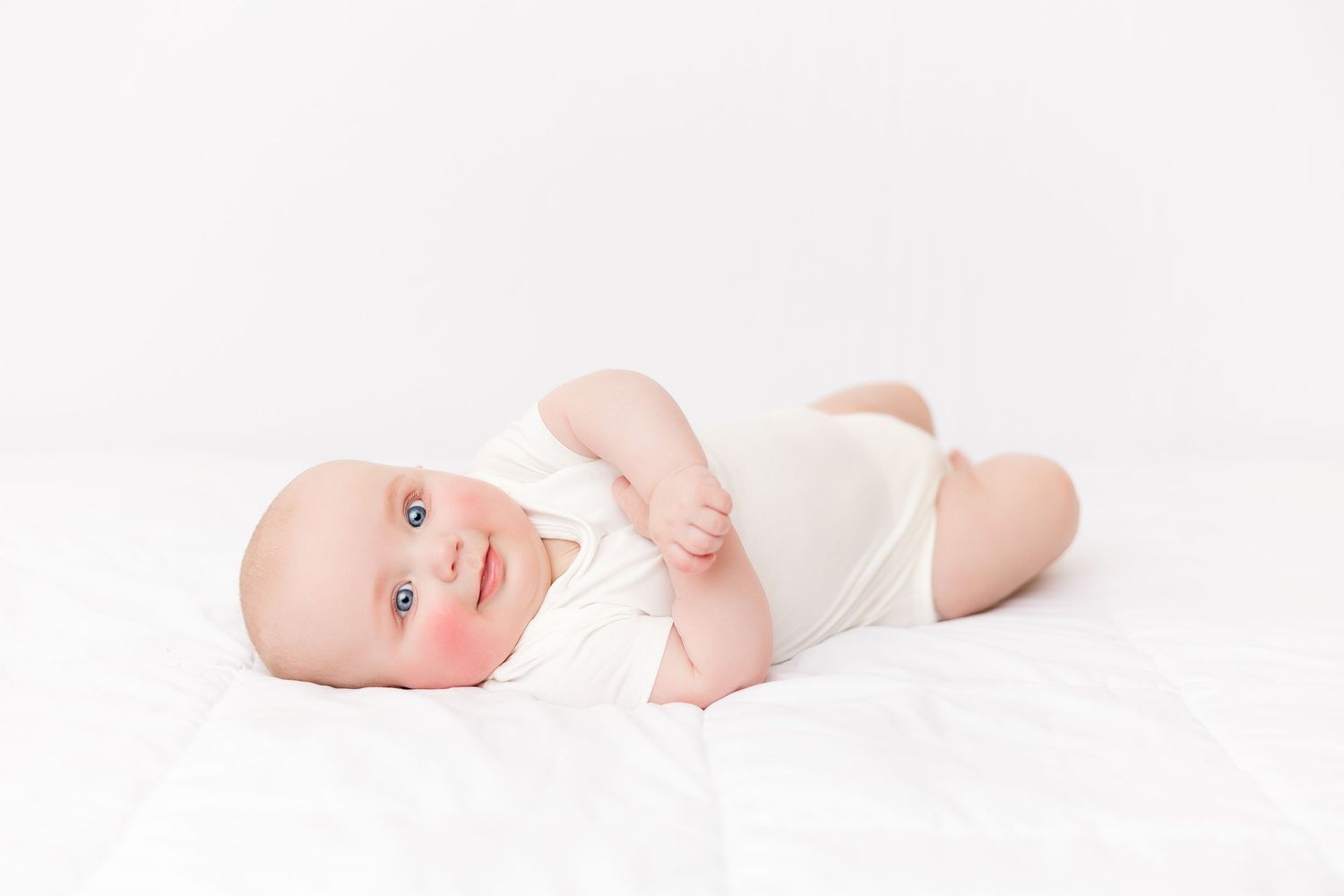 Minimalist white baby photography session on clean background.