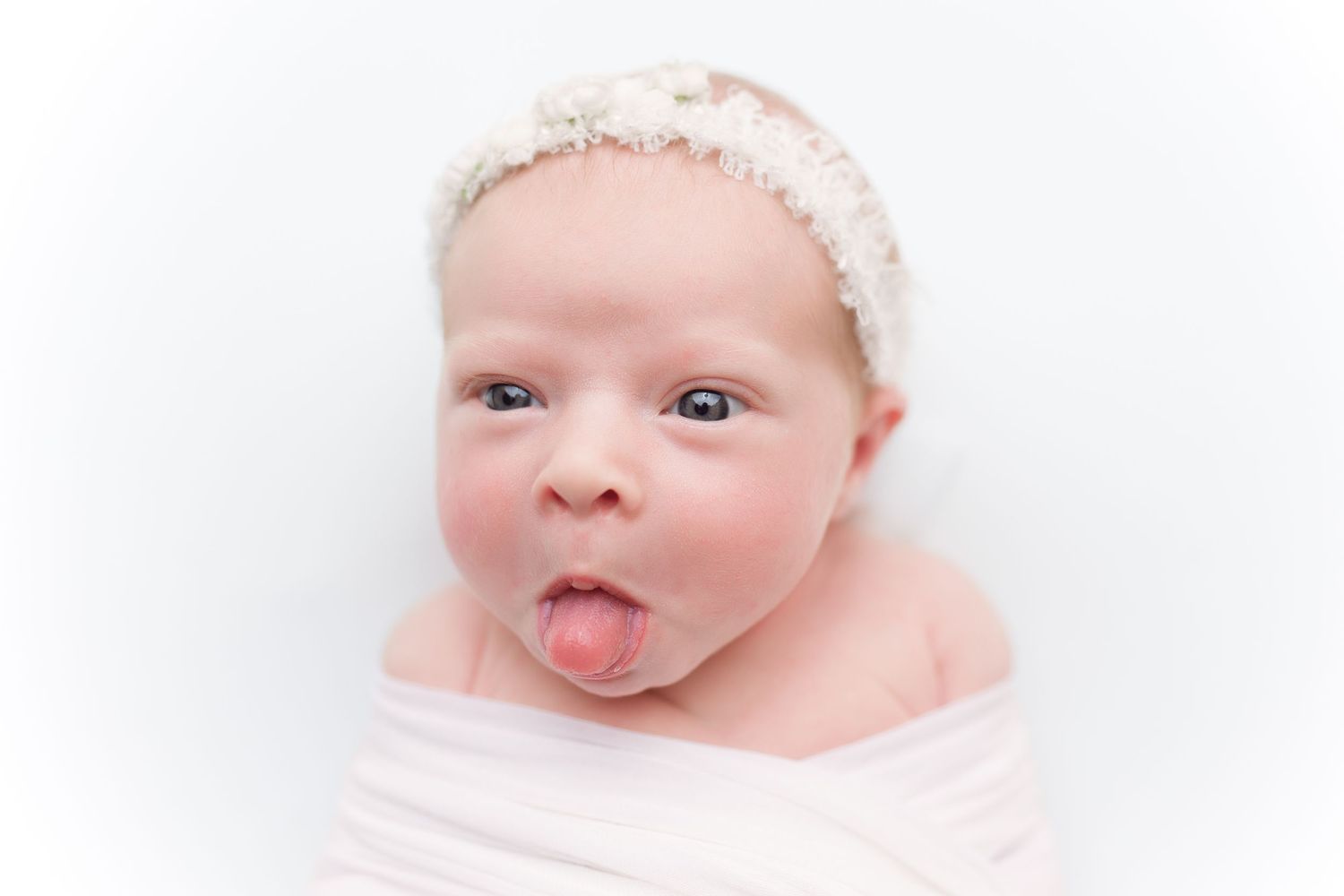 Adorable baby making silly faces in white studio setting.