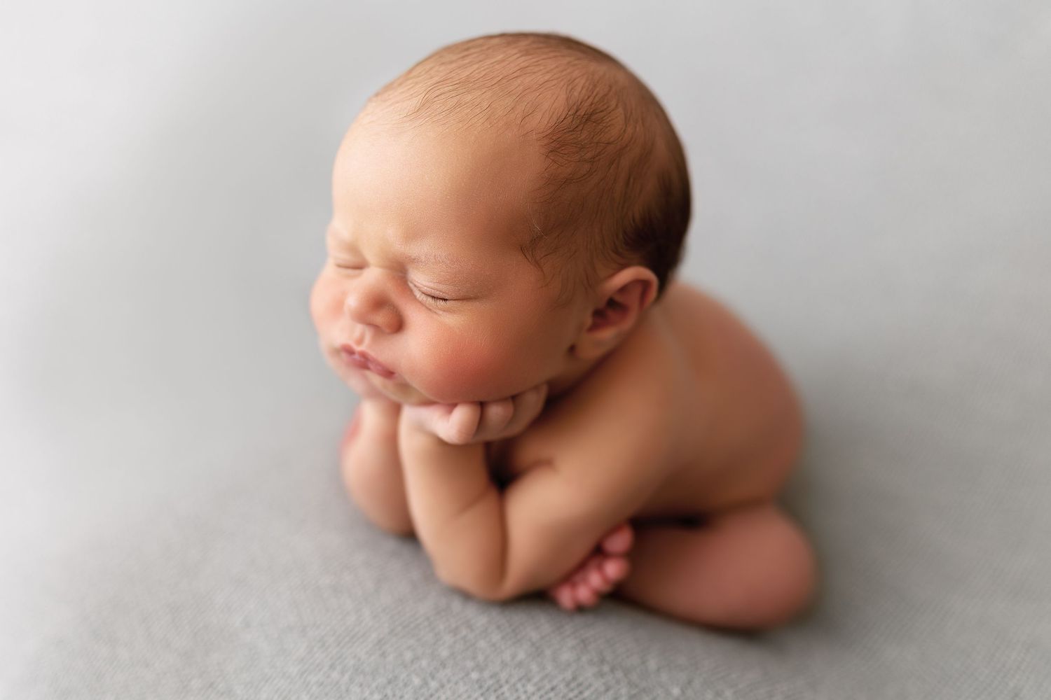 A series of artistic newborn baby photos showing peaceful sleeping poses against a soft gray background.