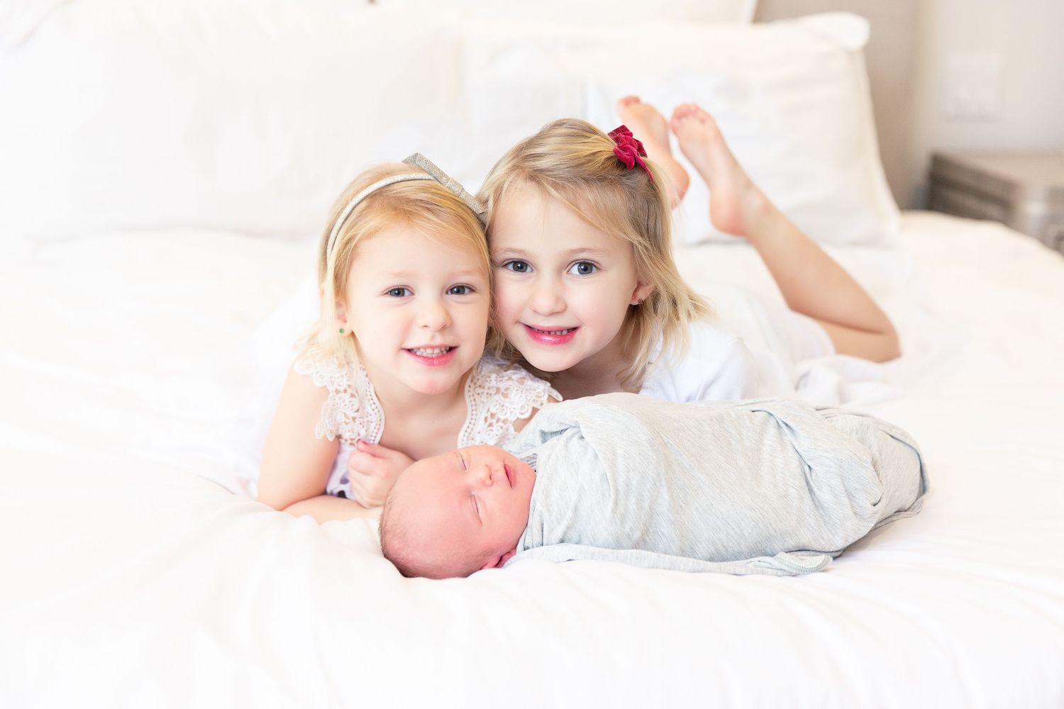 Tender family moment captured on white bedding in a sun-lit bedroom, lifestyle newborn session