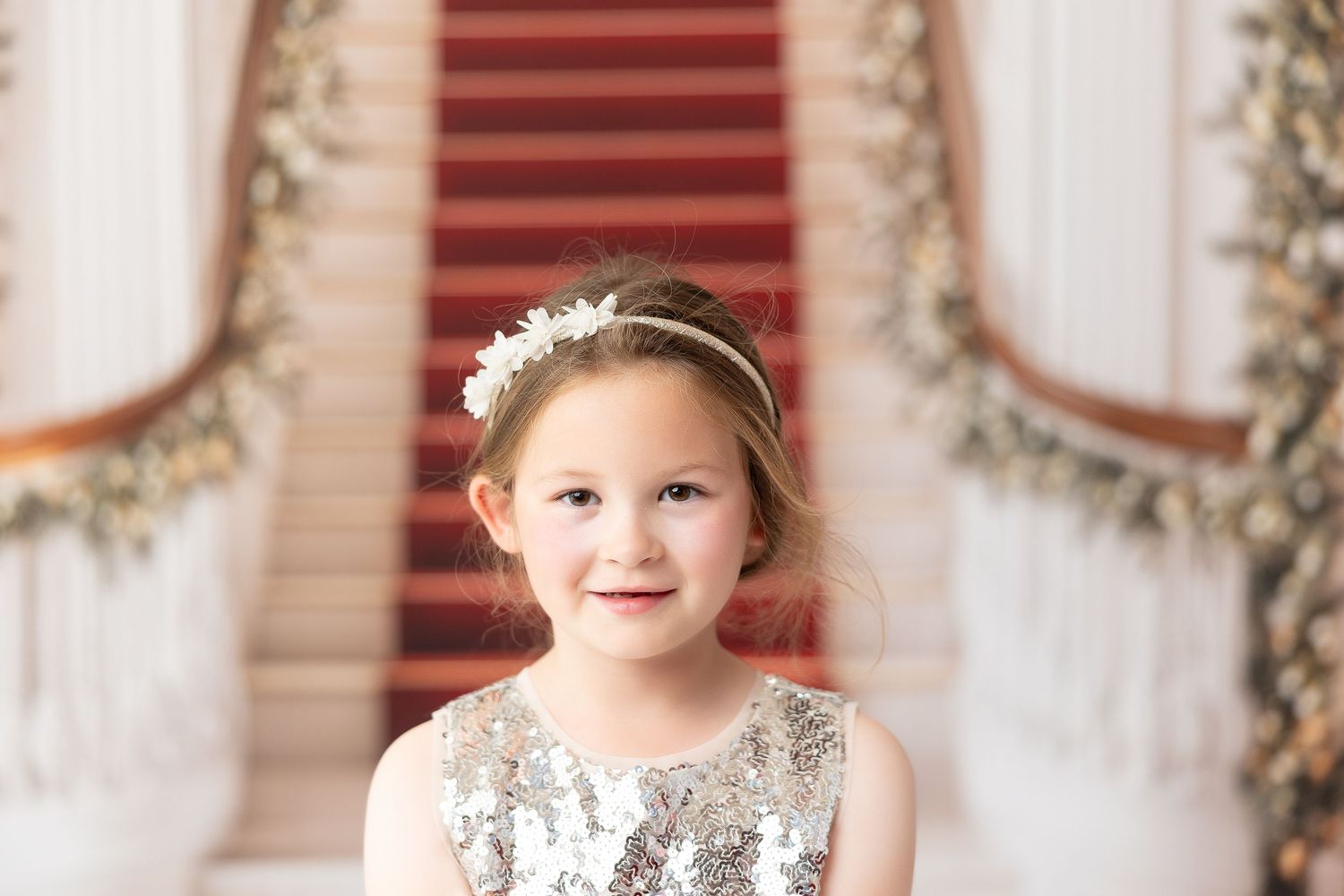 A holiday photo session setup with red shutters, festive wreaths, and decorative elements in warm tones.