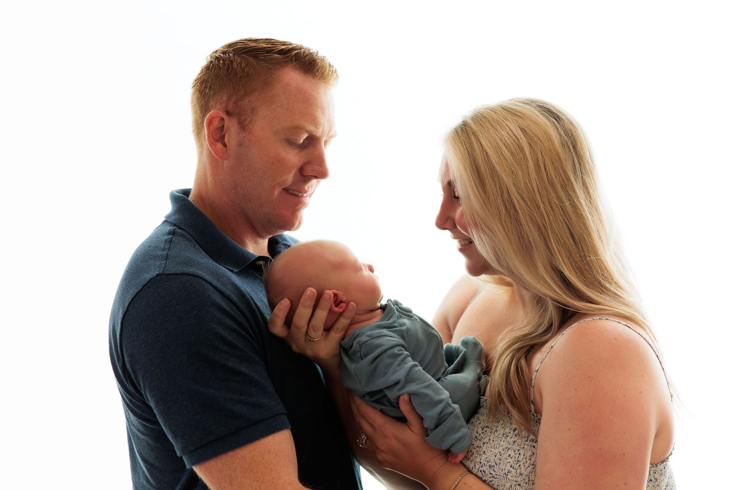Family sharing tender moment with new baby in studio setting.
