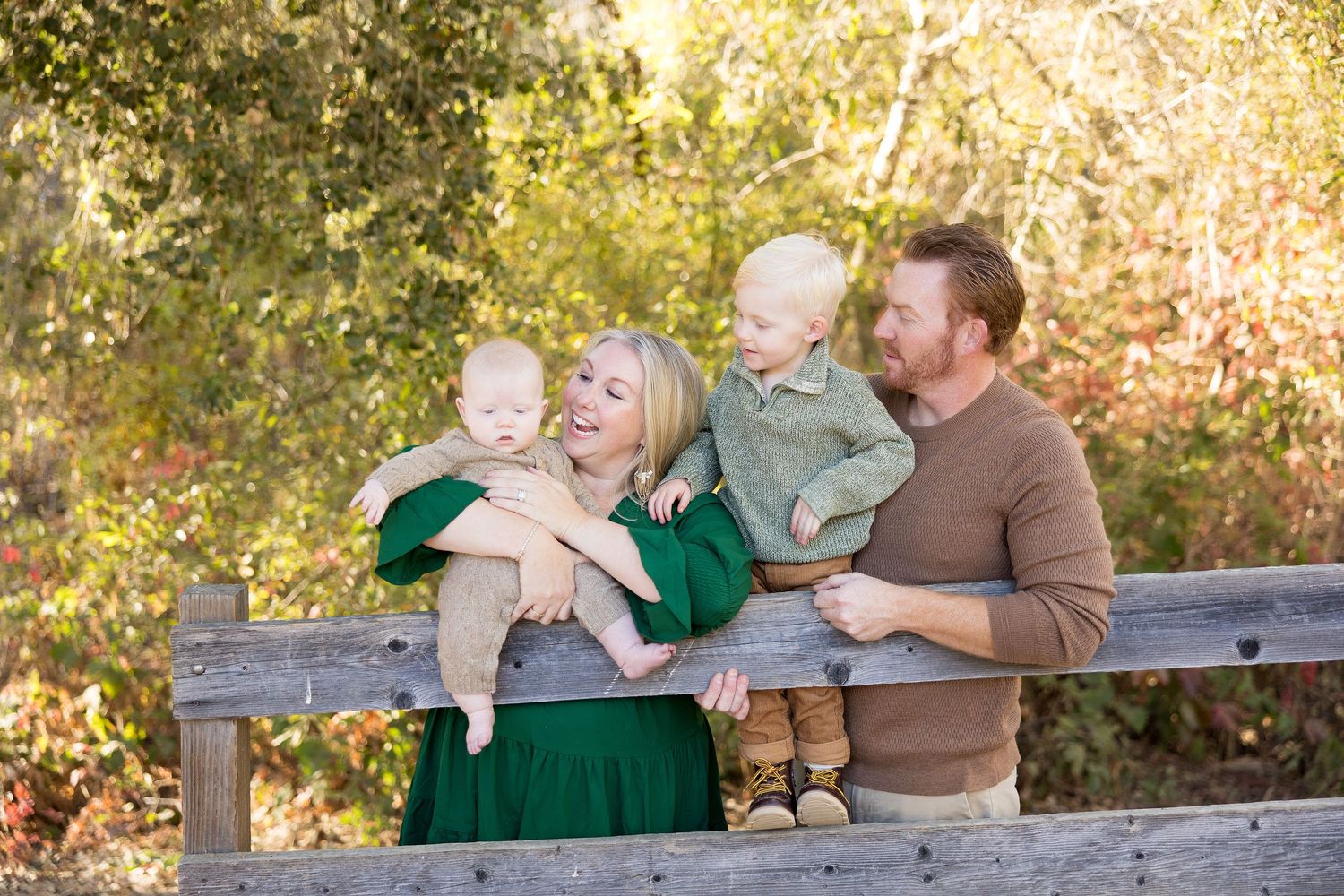 Family sitting together on rustic wooden bench during golden hour photography session.