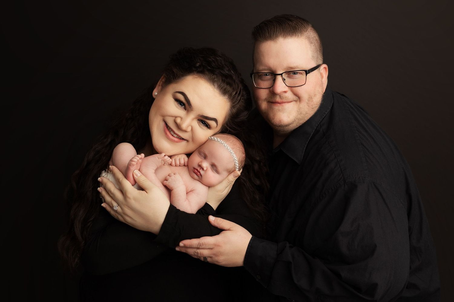 Family photo session featuring loving interactions against dark dramatic background.