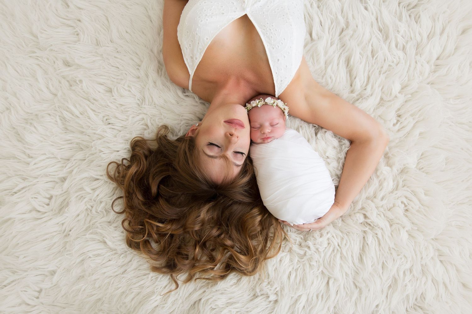 Couple lying together on white fluffy rug during romantic indoor photo session.