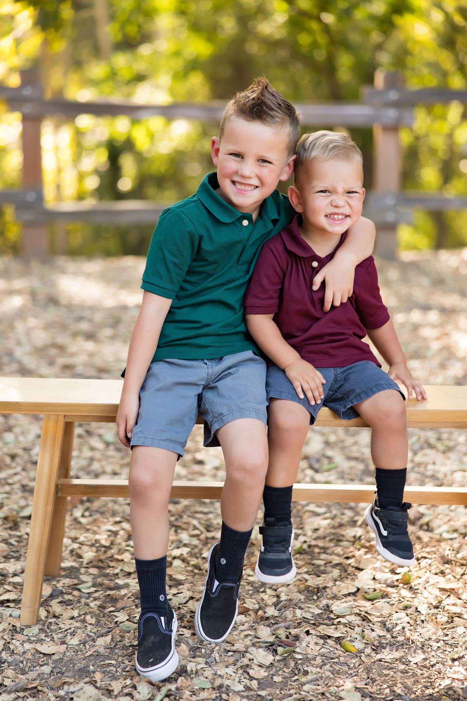 Two children sitting close together on wooden bench in autumn setting.