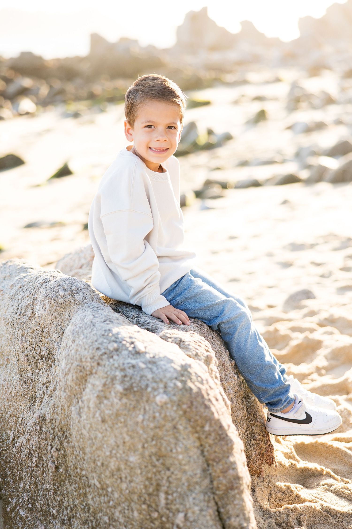 A series of portraits on a large rock formation at the beach during golden hour.
