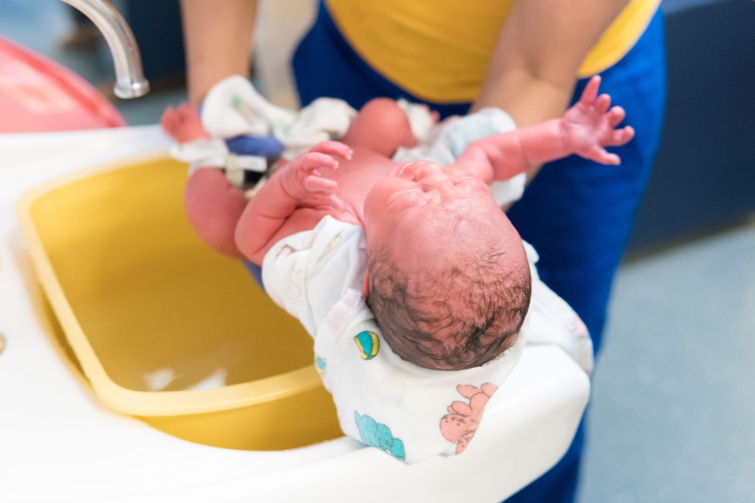 Medical staff performing newborn care procedures in a hospital delivery room setting.