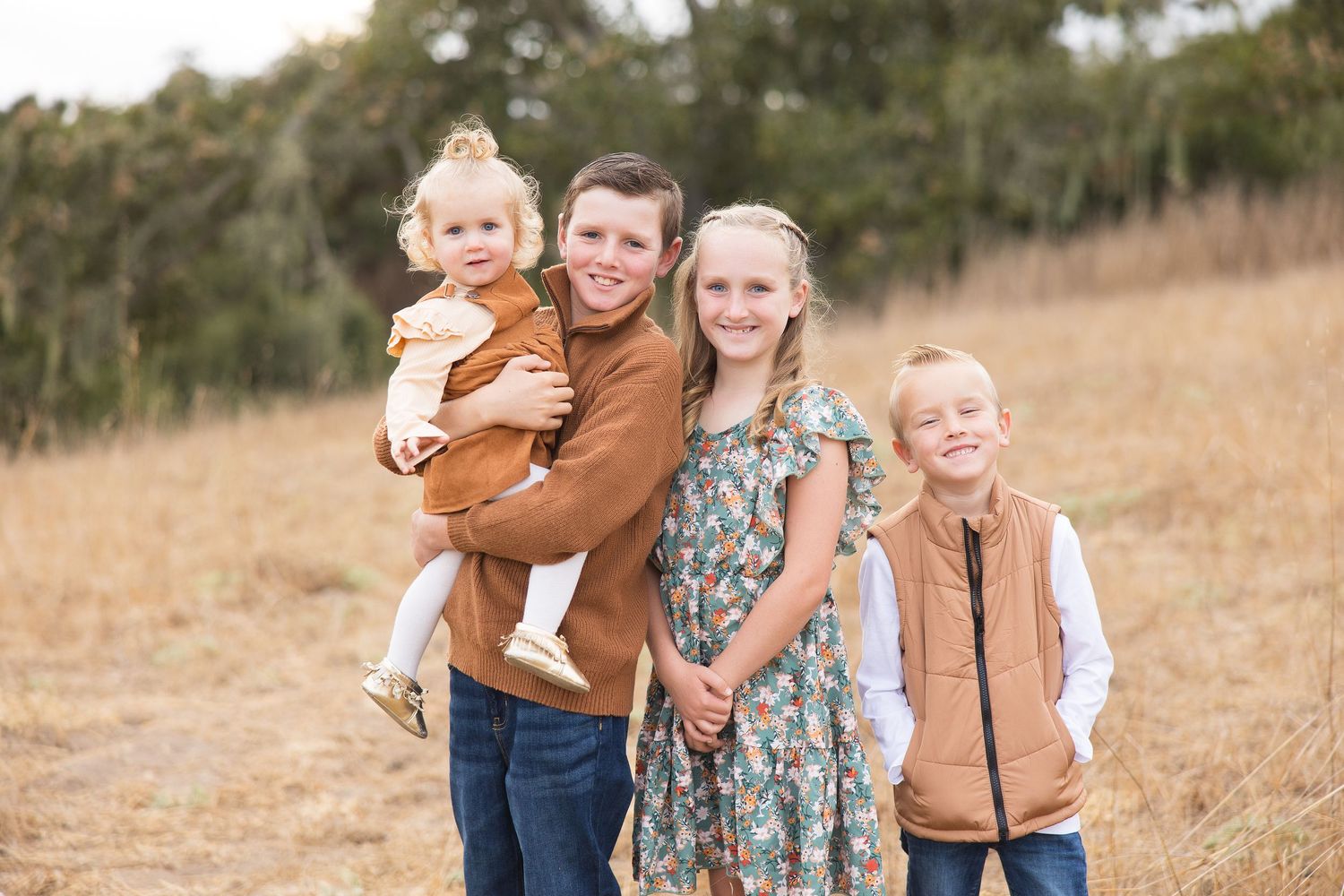 Candid family portraits captured in a golden field during sunset.