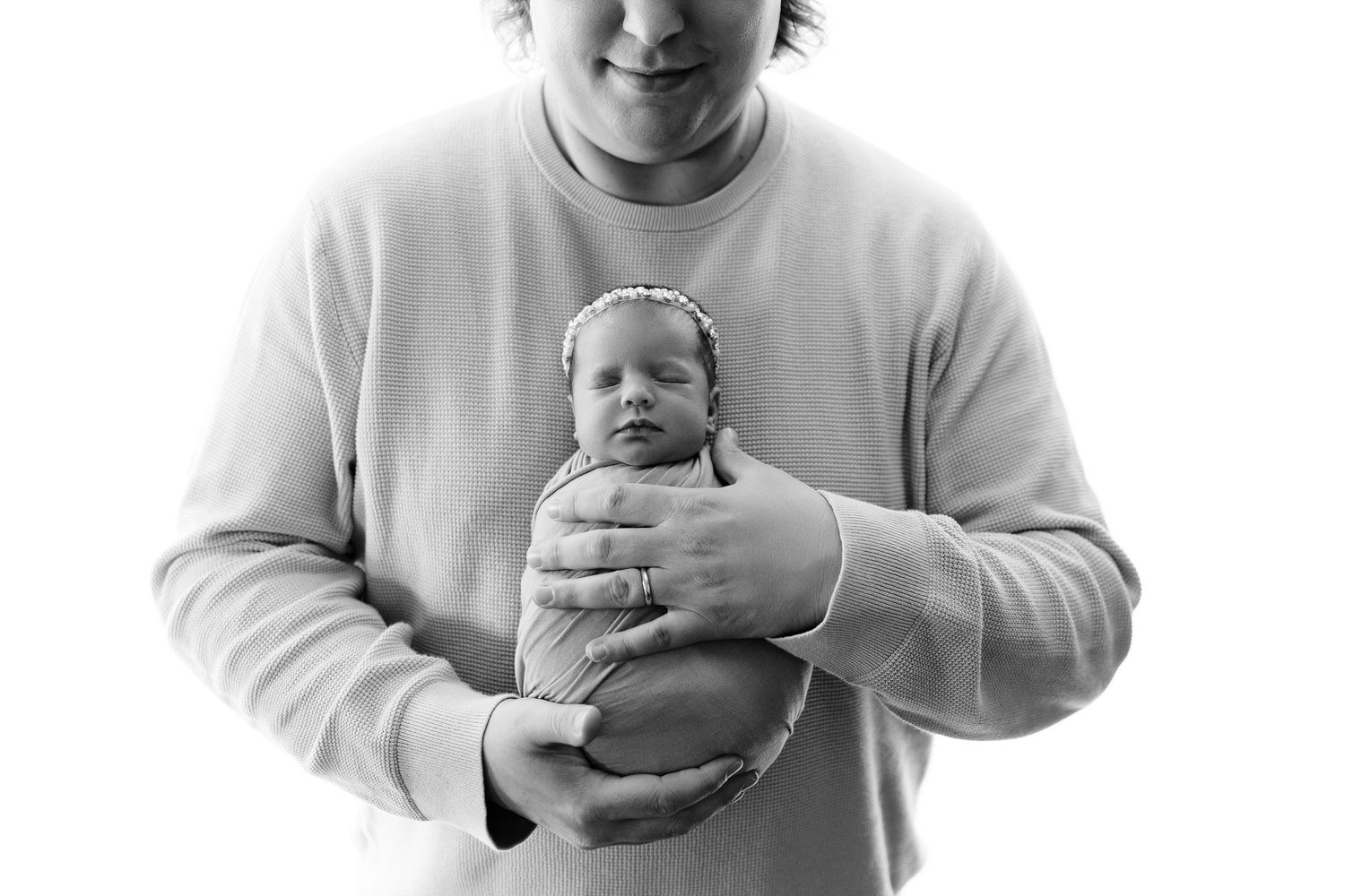Black and white portrait of baby being held gently in hands.
