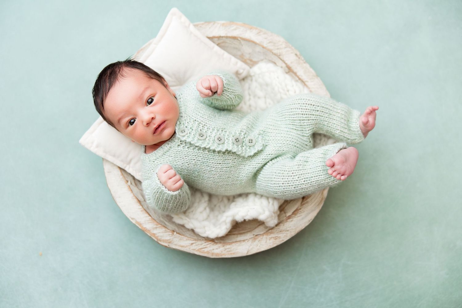 Set of newborn photos featuring baby in mint green outfit on light aqua background.