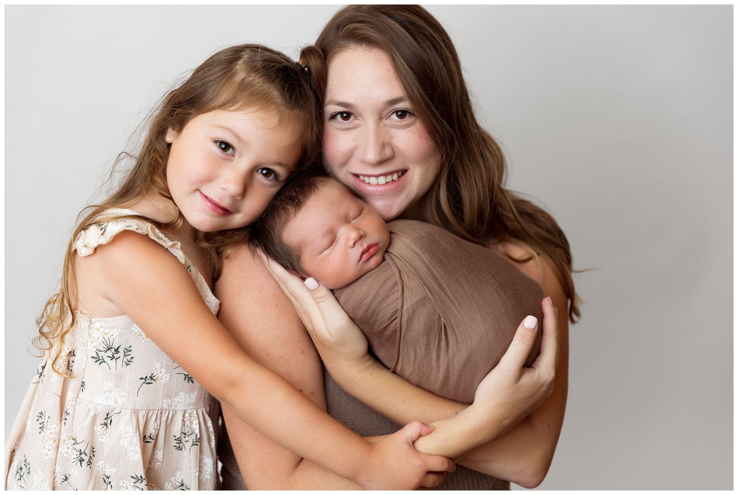 Two people embrace warmly against a neutral background in a tender family portrait setting.
