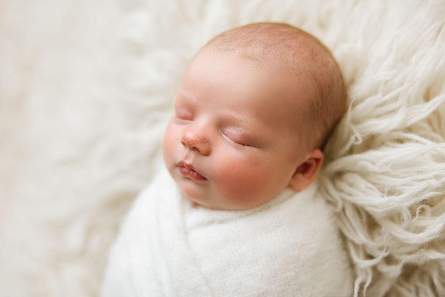 A sleeping newborn baby lies peacefully on soft white fabric in a series of connected portrait photographs.
