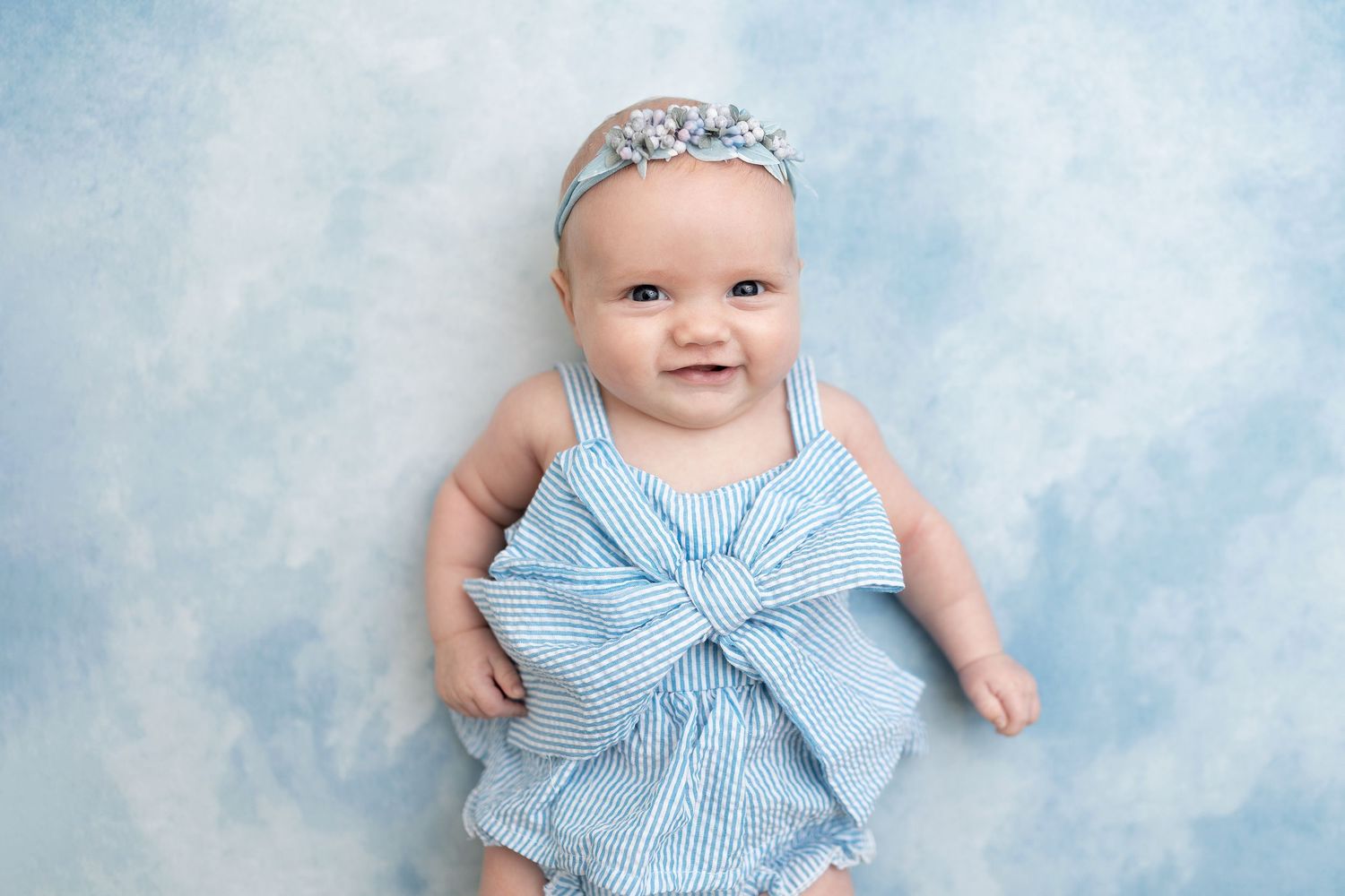 Baby photography session featuring light blue outfits and soft cloud-like backgrounds.