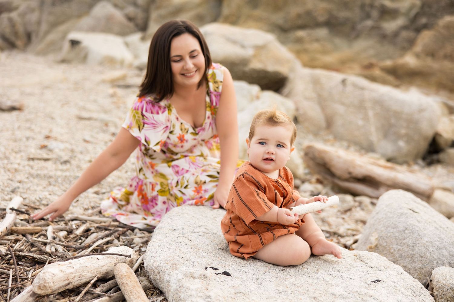 Family members sitting together on coastal rocks during sunset photoshoot.