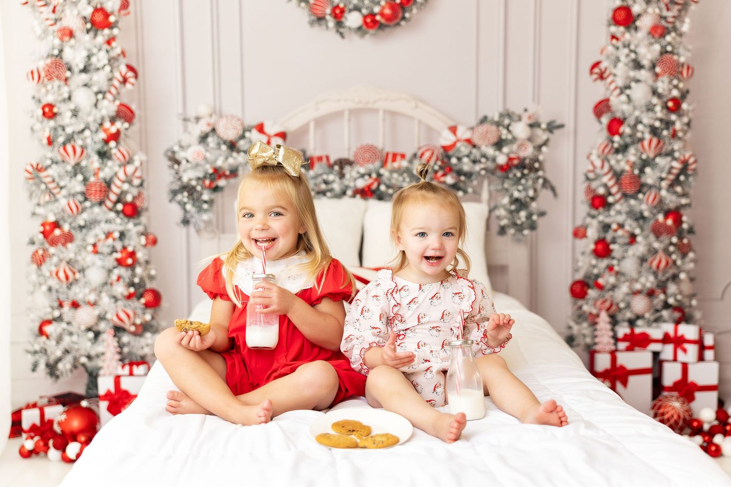 Christmas themed portrait session with kids enjoying cookies against floral holiday backdrop.