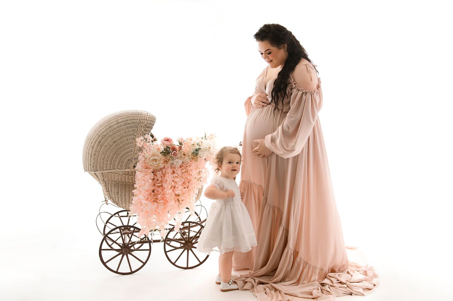 Dreamy pink maternity photo session featuring vintage baby carriages and soft feminine styling.