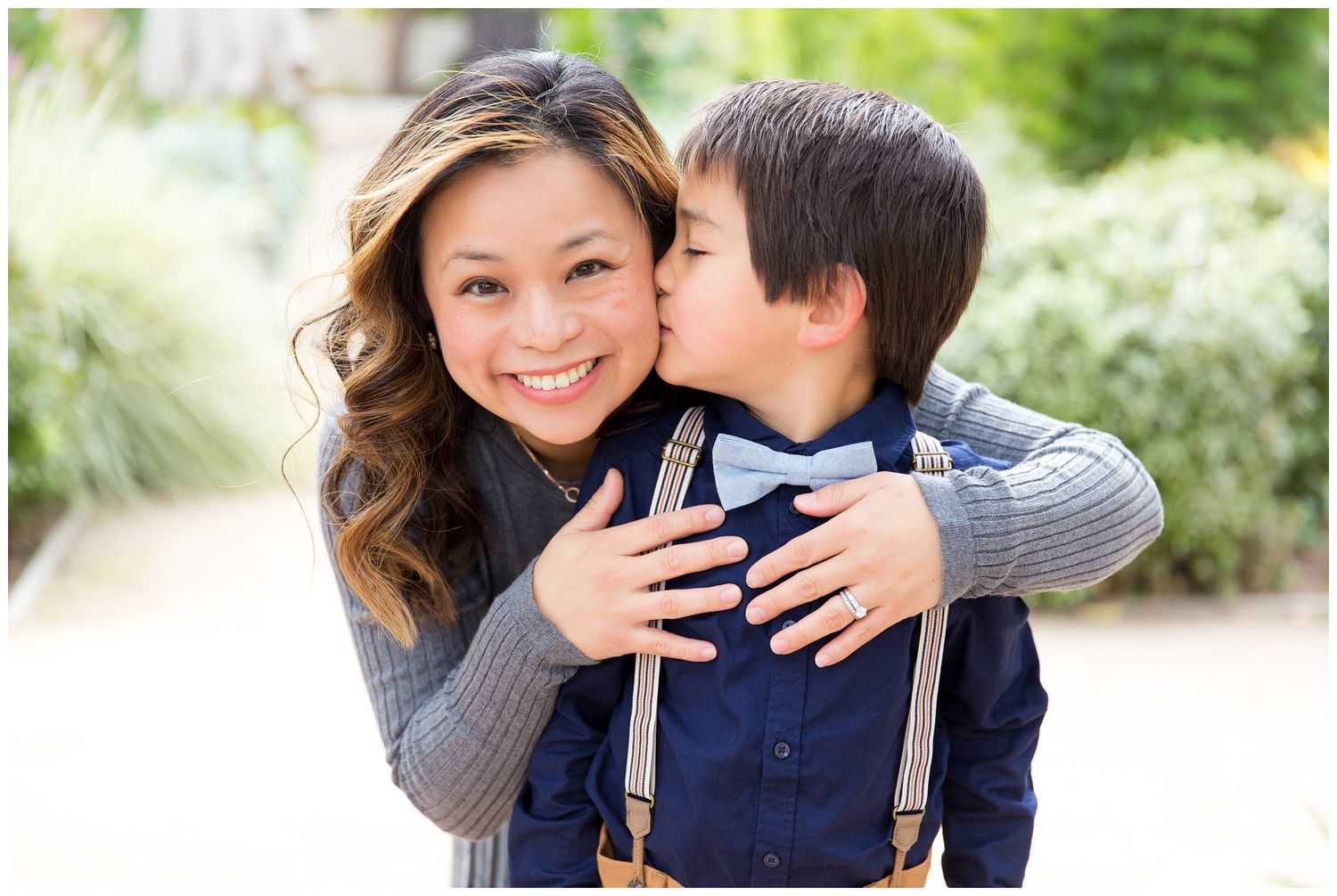 A family shares tender moments together in a series of outdoor portraits with natural lighting and greenery.