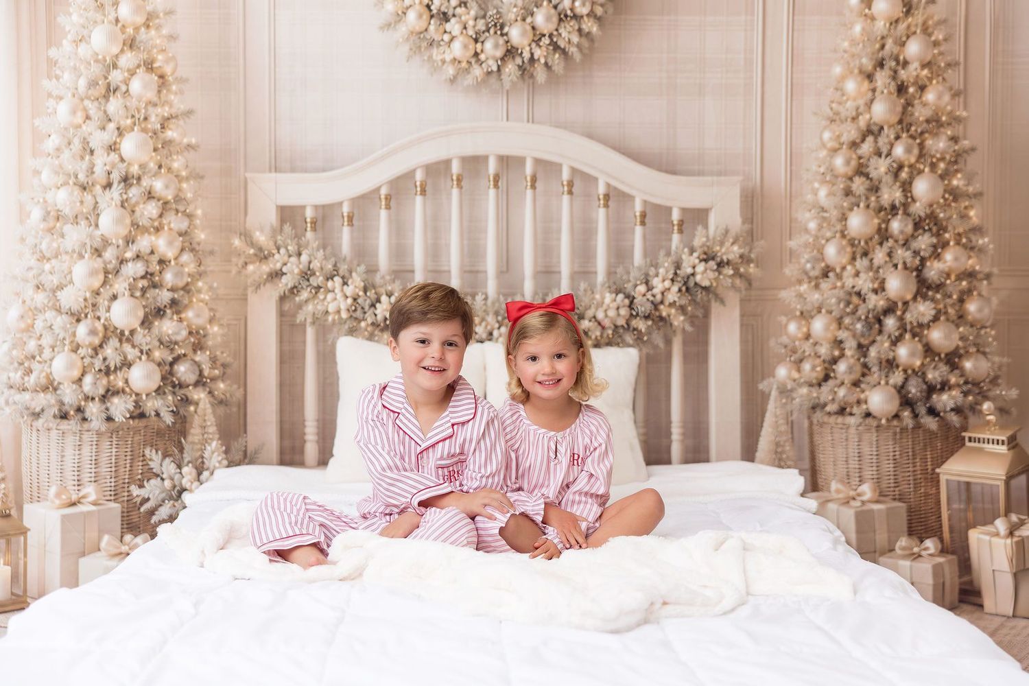 Brother and sister in red striped Christmas pajamas on a neutral Christmas bed set at a Milk and Cookies mini session
