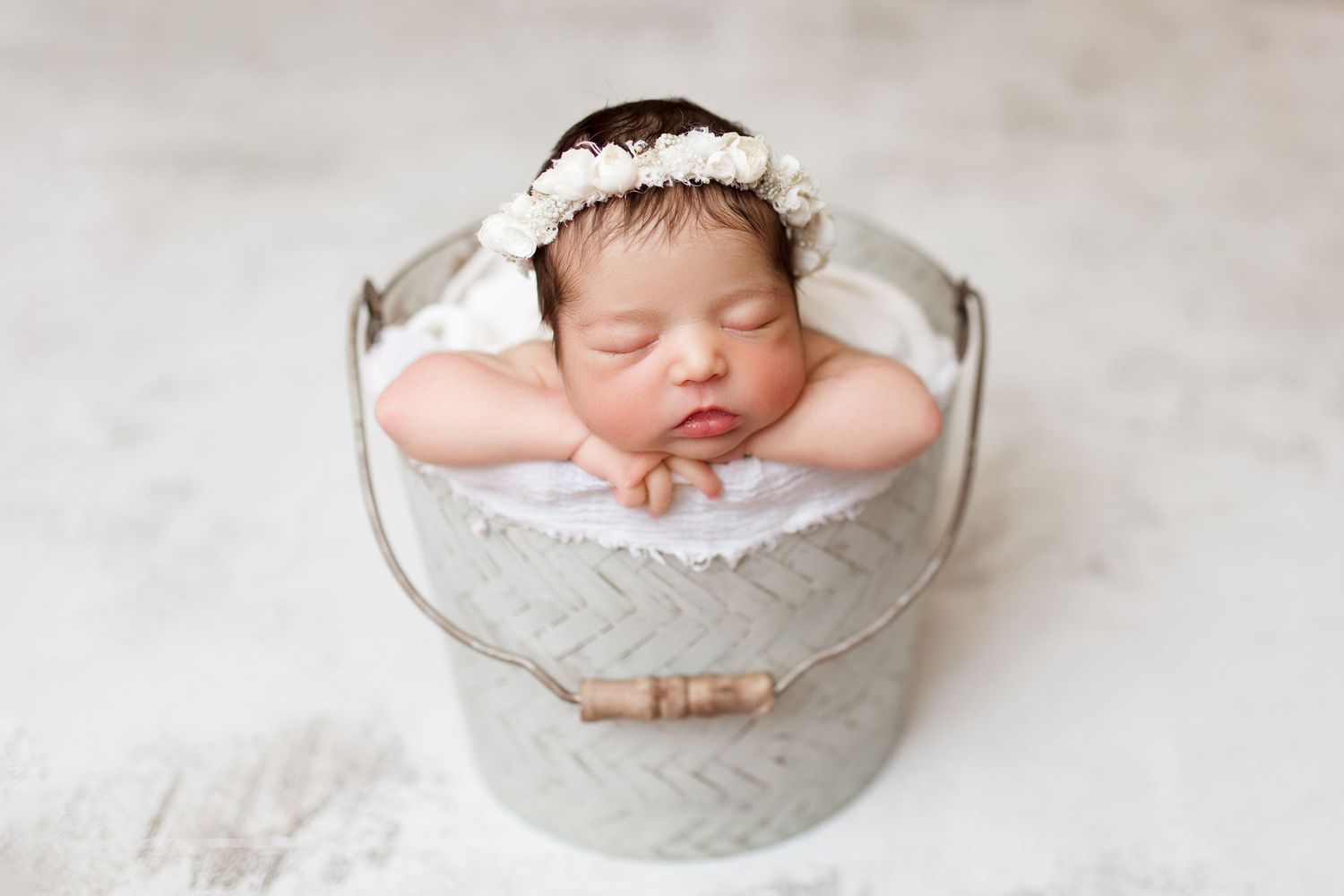 Sleeping baby posed in antique white metal container.