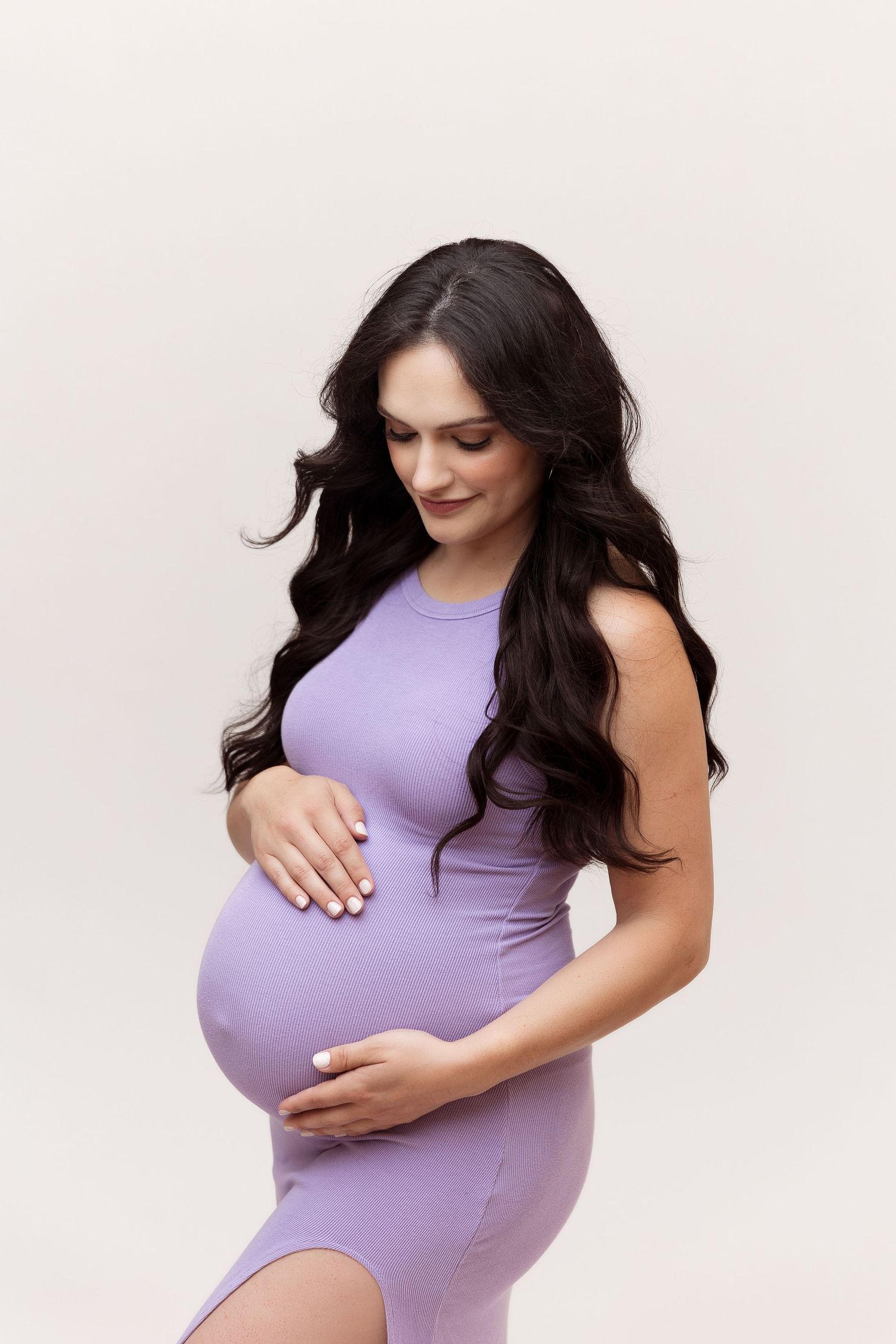 Maternity photos showing woman in fitted purple dress highlighting pregnancy.